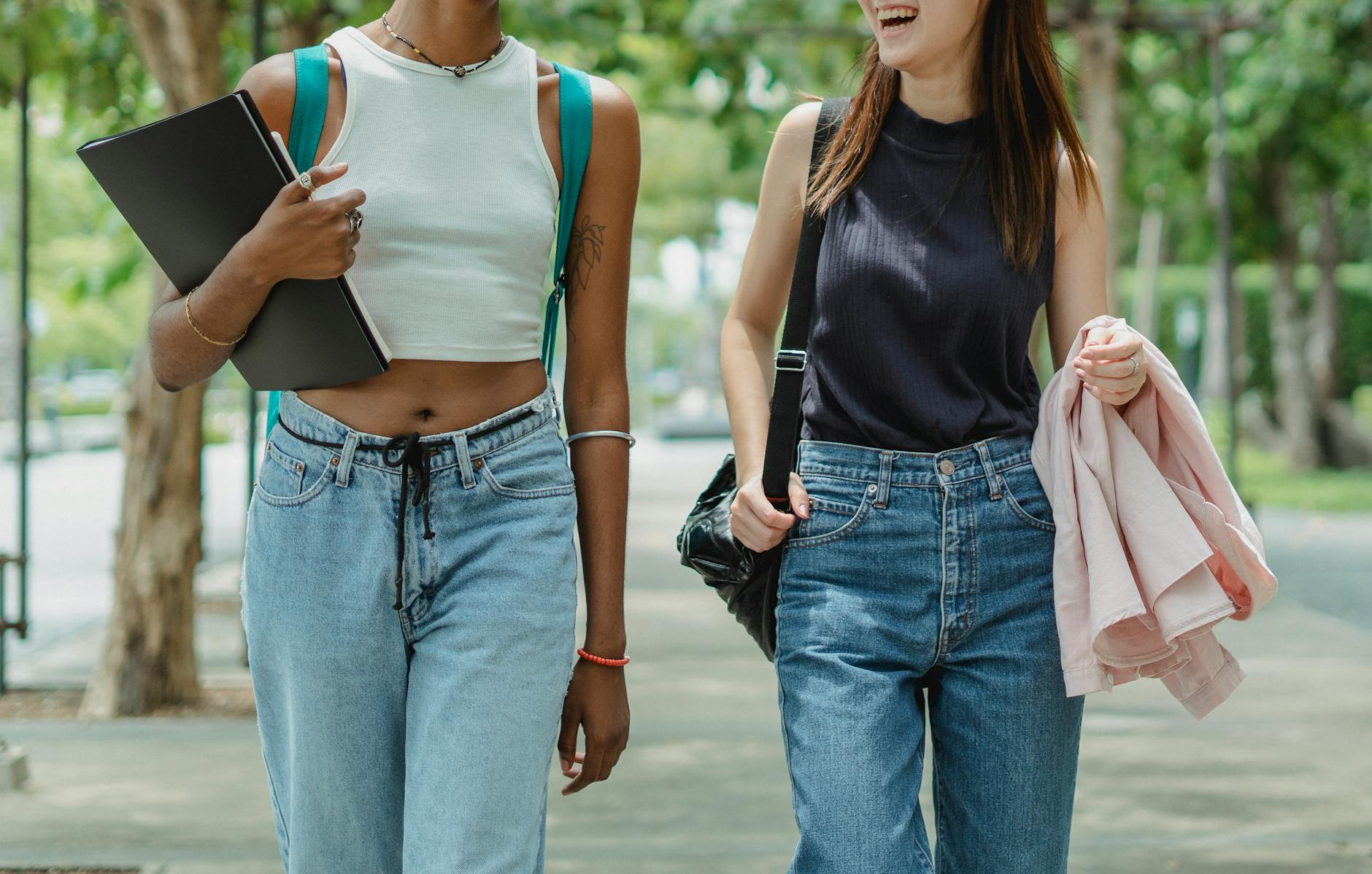 A close-up of a student's hands writing in a notebook next to a colorful backpack and a pair of glasses.