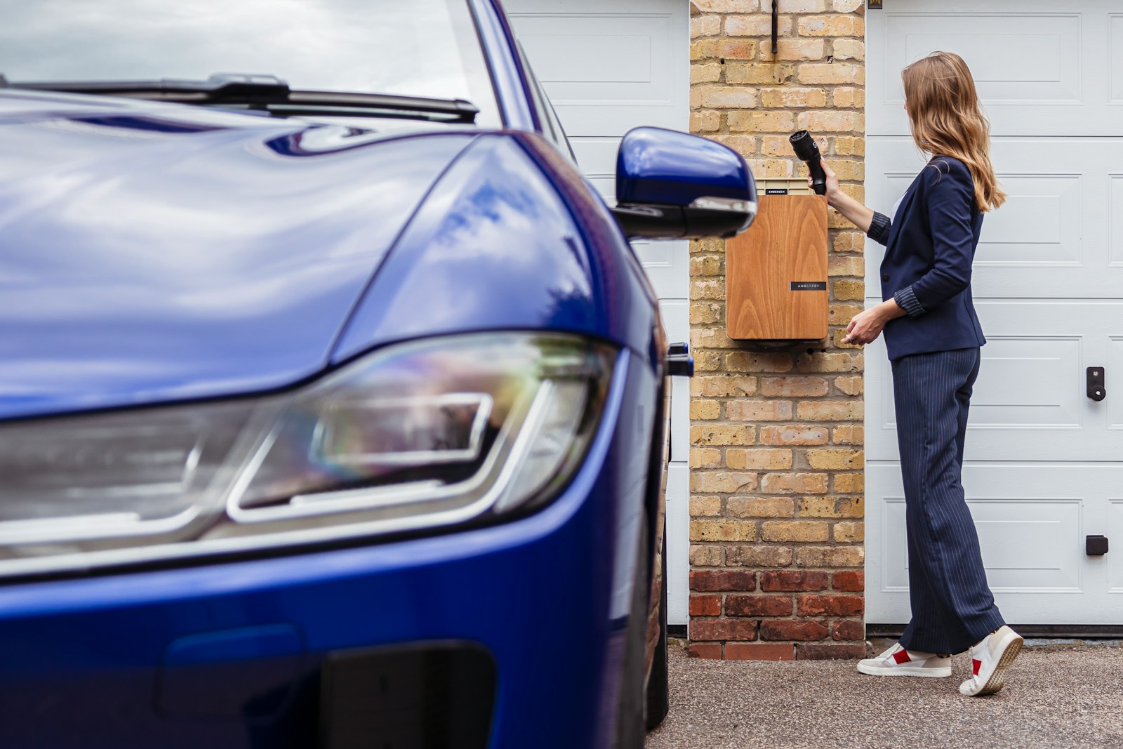 An EV owner beside her car at home