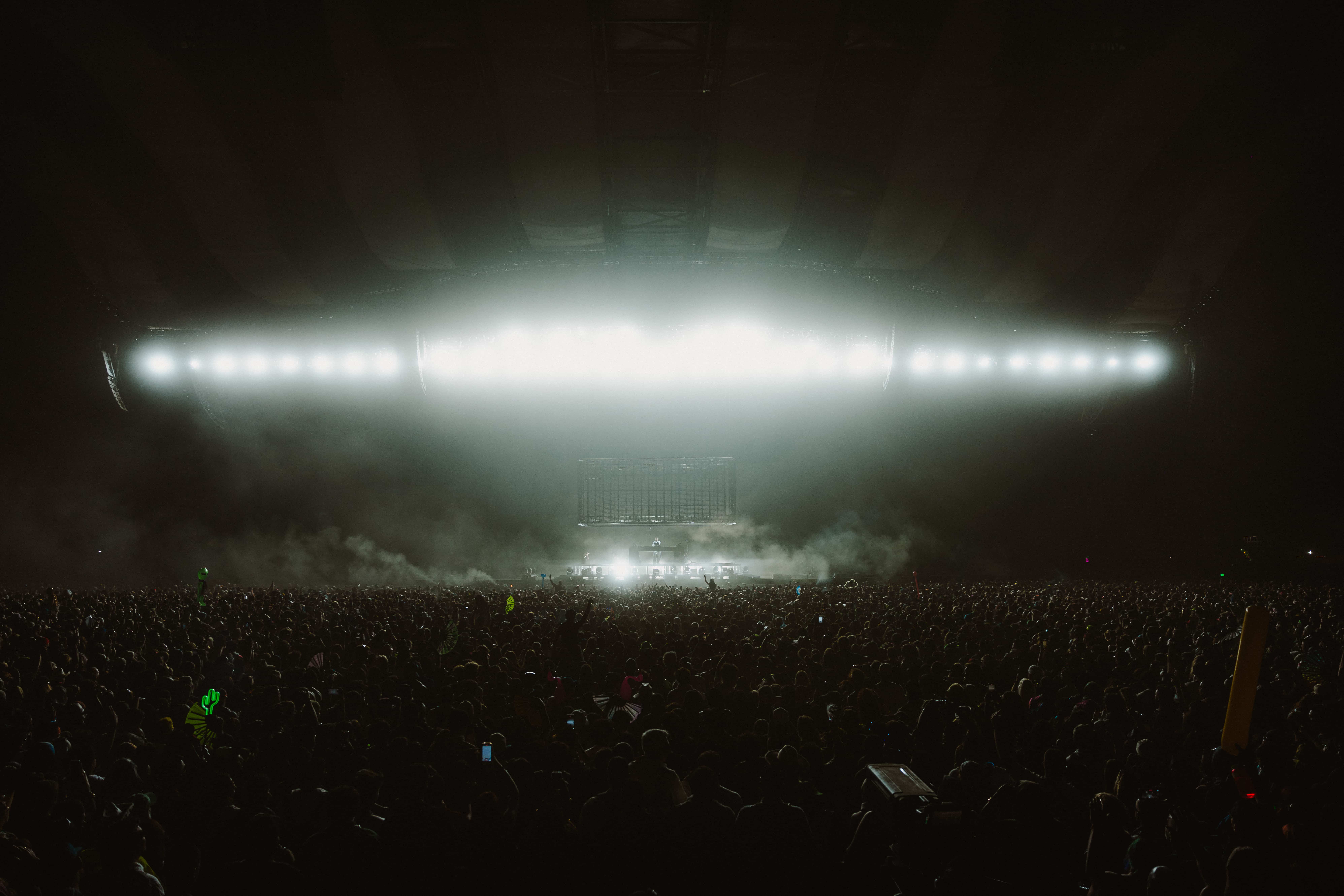 Wide shot of MAU P performing at Coachella 2025 with a massive crowd and bright stage lighting cutting through haze, captured by A World Away creative director Brandon Densley