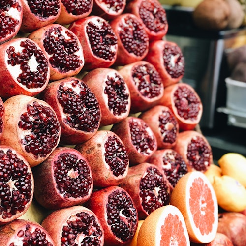 A display of stacked pomegranates and halved grapefruits at a market stall.