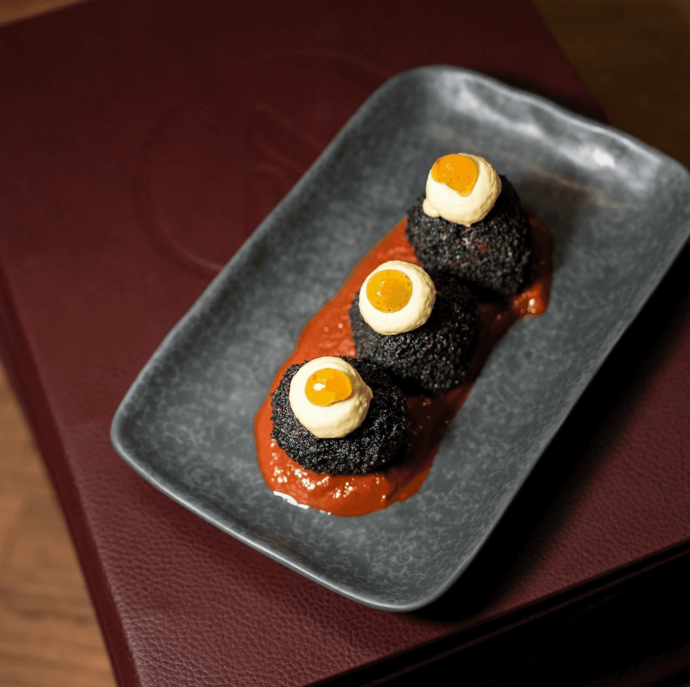 Boule de feu, arancini de scarmorza avec yuzu kosho servis sur sauce tomate, spécialité du restaurant LAVA à Paris, illustrant une cuisine créative et audacieuse dans le Quartier Latin.