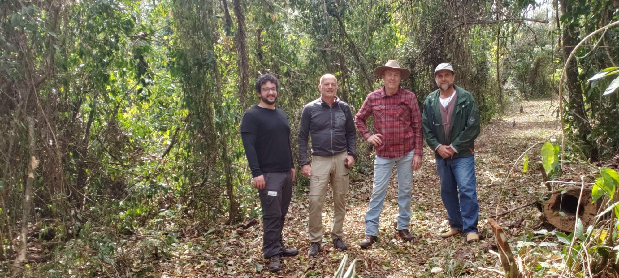 Quatro homens posando em trilha de mata seca durante visita às RPPNs do projeto