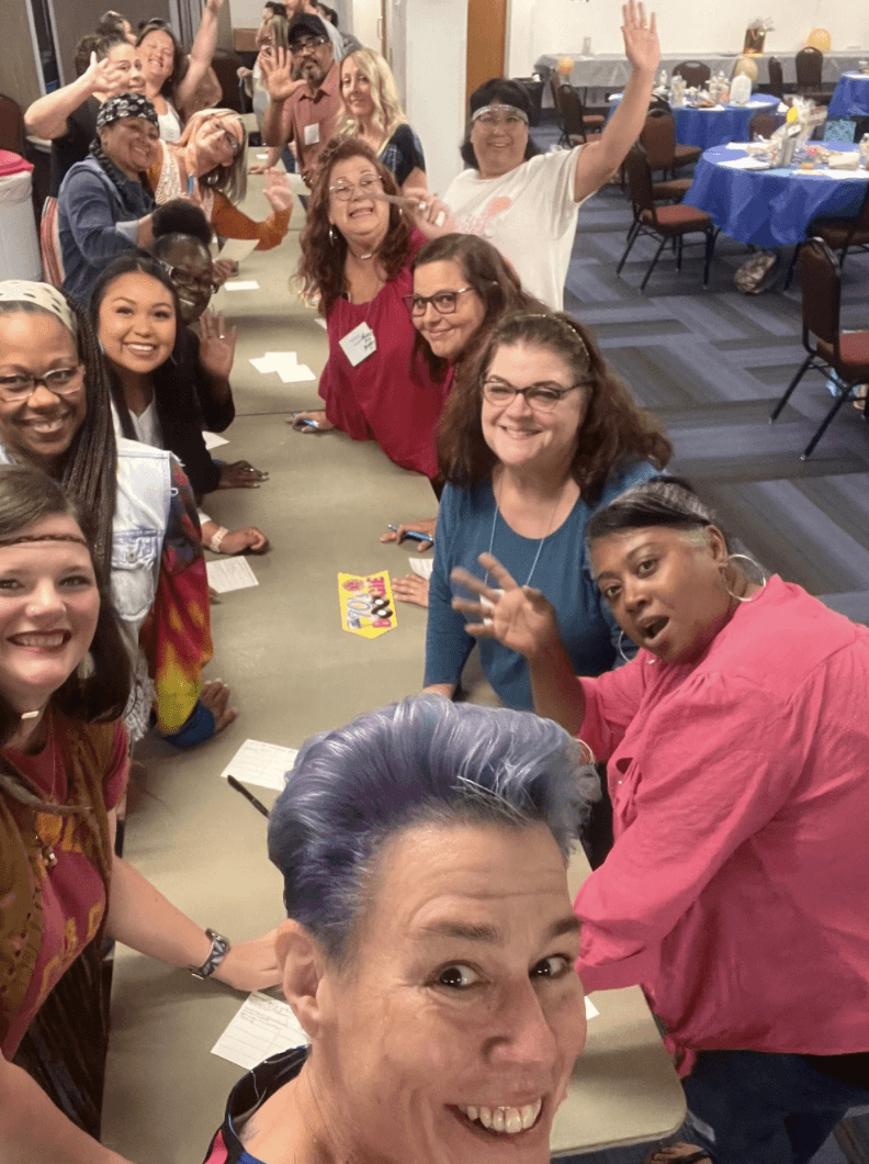 A diverse group of workshop participants with Linda Clark waving hello for a group photo