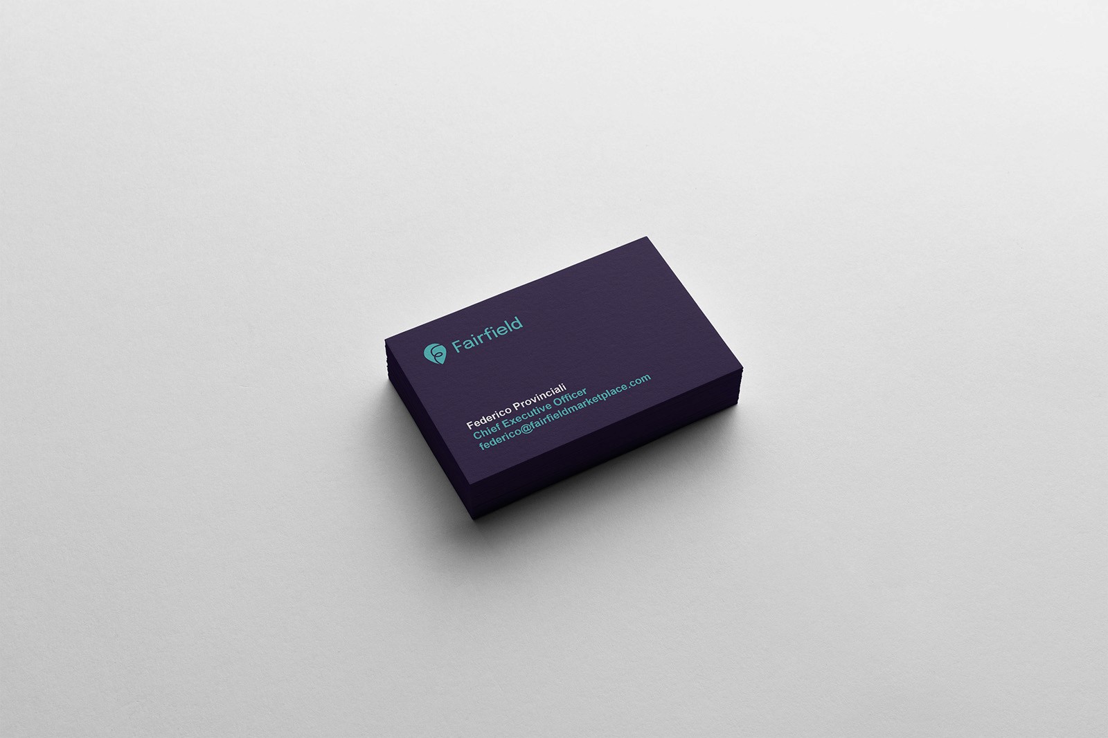 Business cards featuring teal Fairfield logo on Almost Black background 