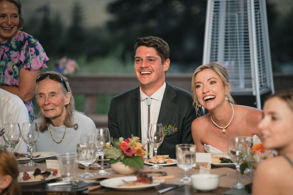 Newlyweds smiling at their reception table