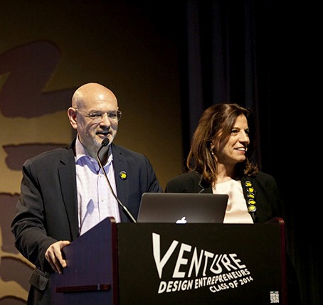 an old man giving a speech and an older women standing next to him