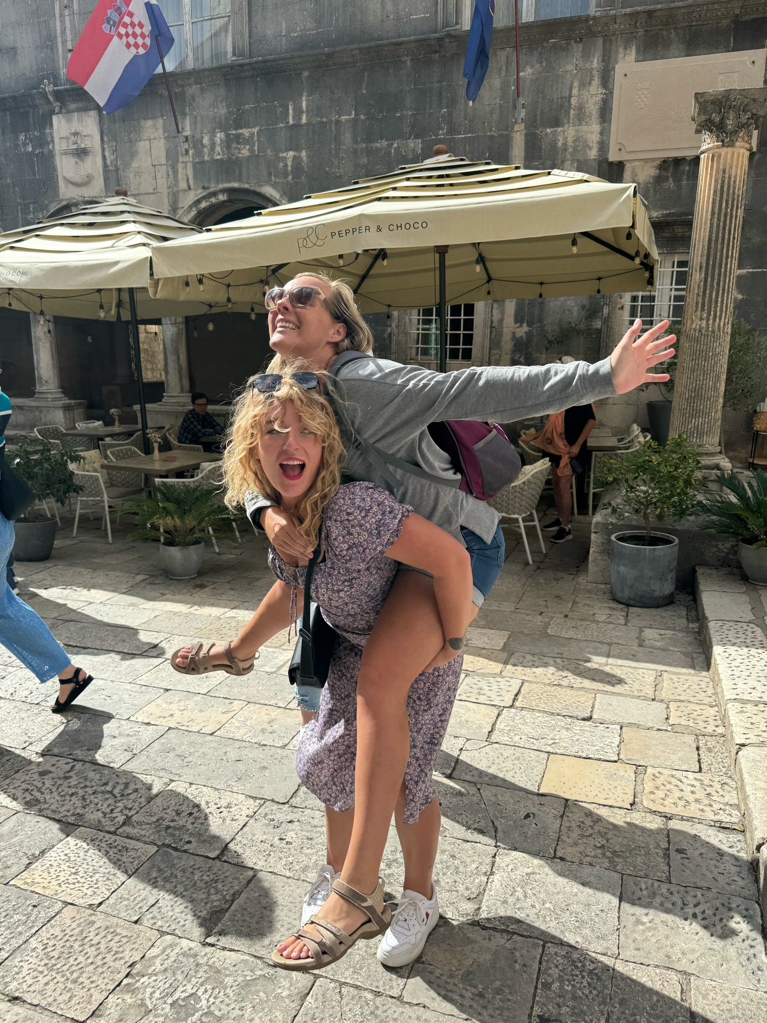 Tess Meijer en een reiziger lachen op een terras tijdens een Off The Norm-getaway — speelse momenten en diepe verbinding in kleine groepen.