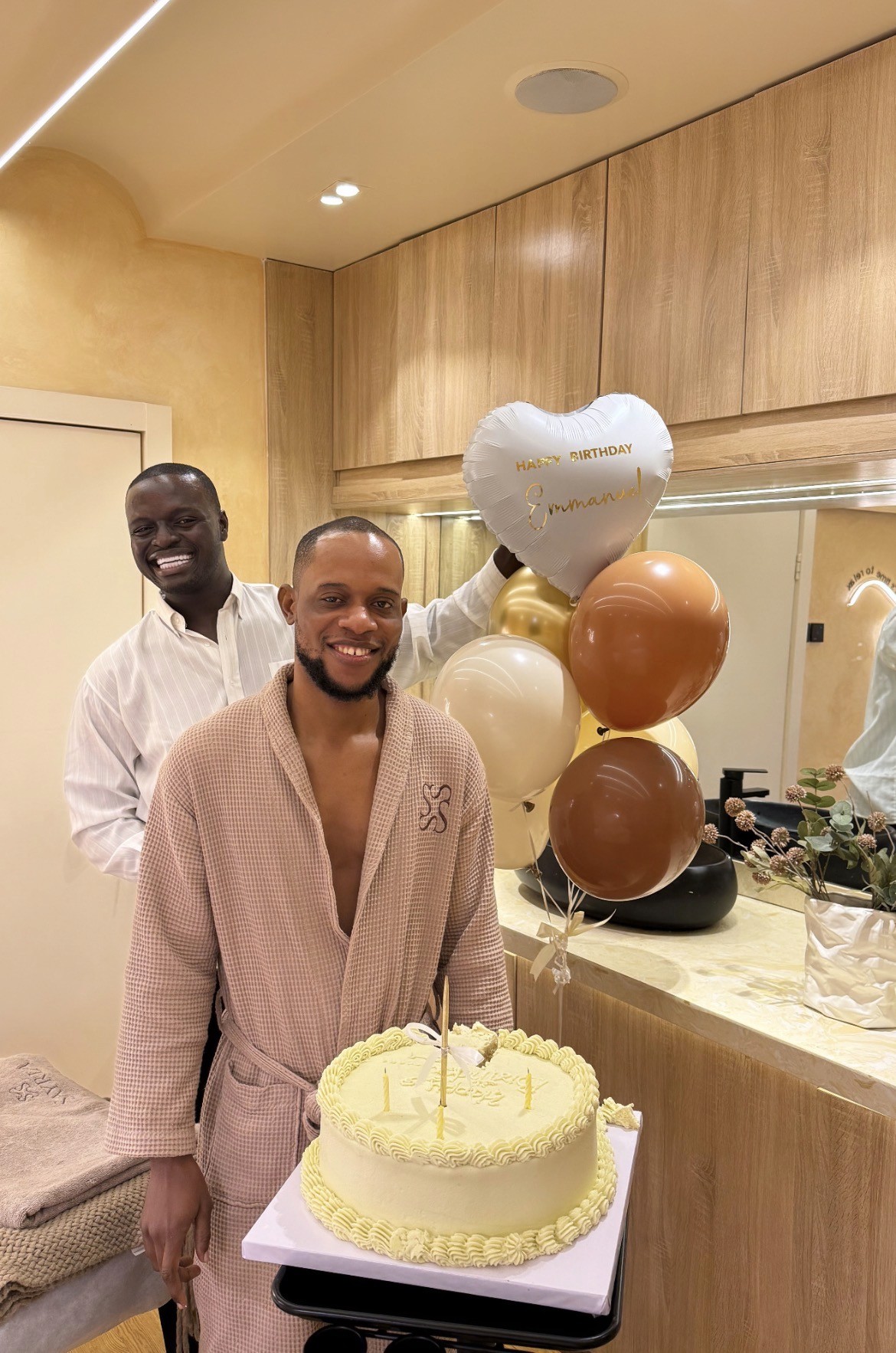 Man with tousled hair sitting at a cluttered desk in a dimly lit room. Warm, orange lighting creates a moody and contemplative atmosphere.