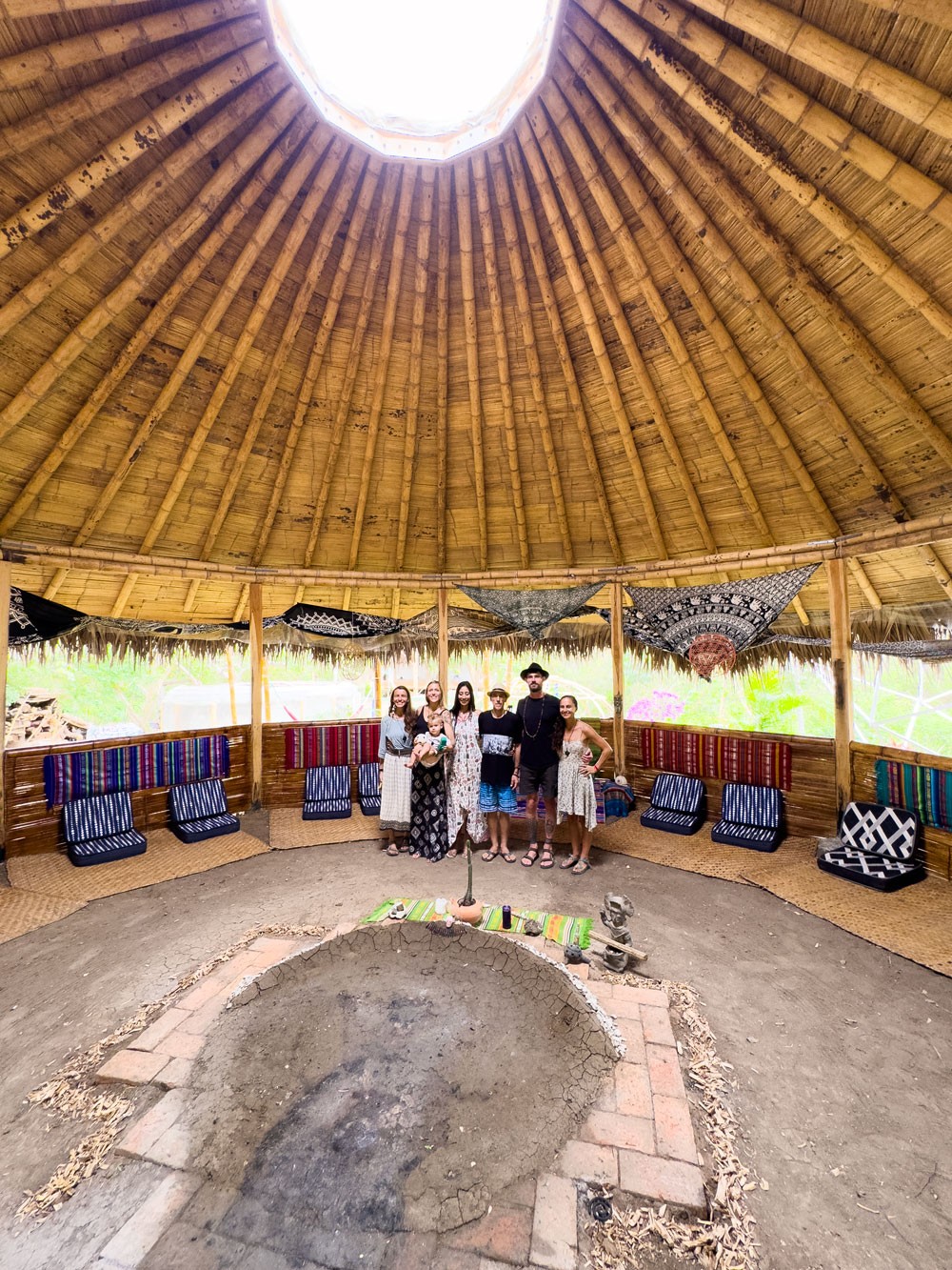 A group of people stood within a large round Ecuadorian hut in the jungle.