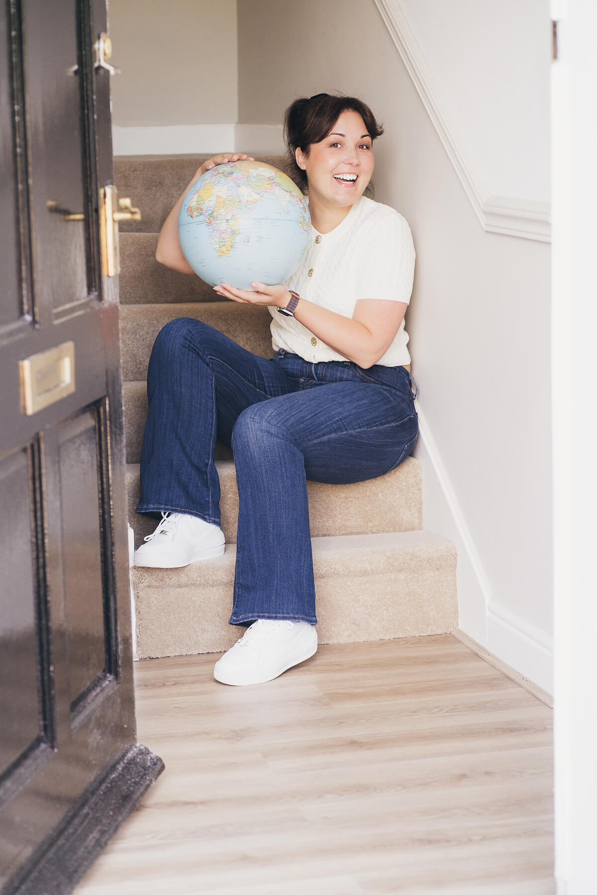 Aniko Rucz holding a globe, representing her international experience and journey in short-term rental hosting