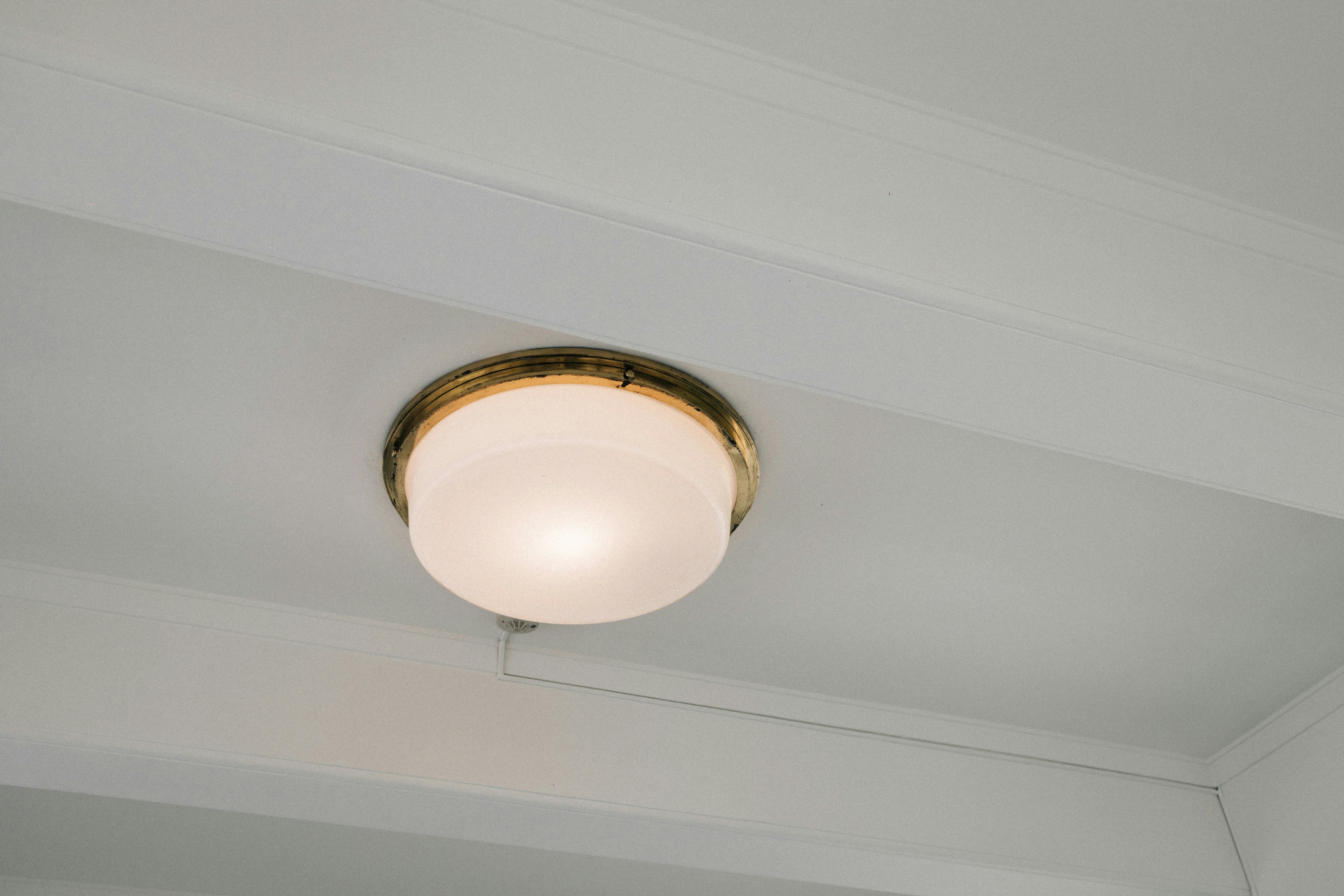 A white ceiling light fixture with a brass trim.
