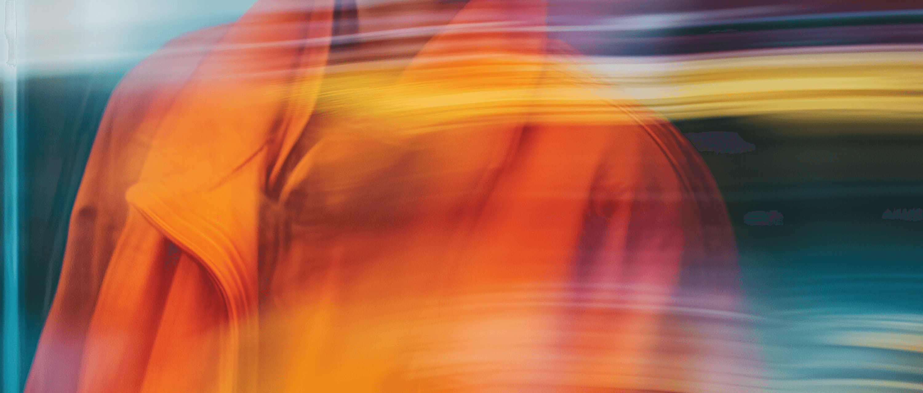 Blurry image of a person wearing an orange robe, creating an abstract and indistinct visual effect.