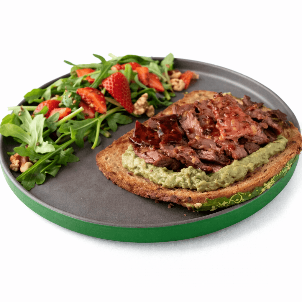 A large, perfectly seared fillet of salmon with crispy skin and a herb glaze, garnished with microgreens, fresh dill, and lemon wedges, presented on a dark wooden board against a black background.