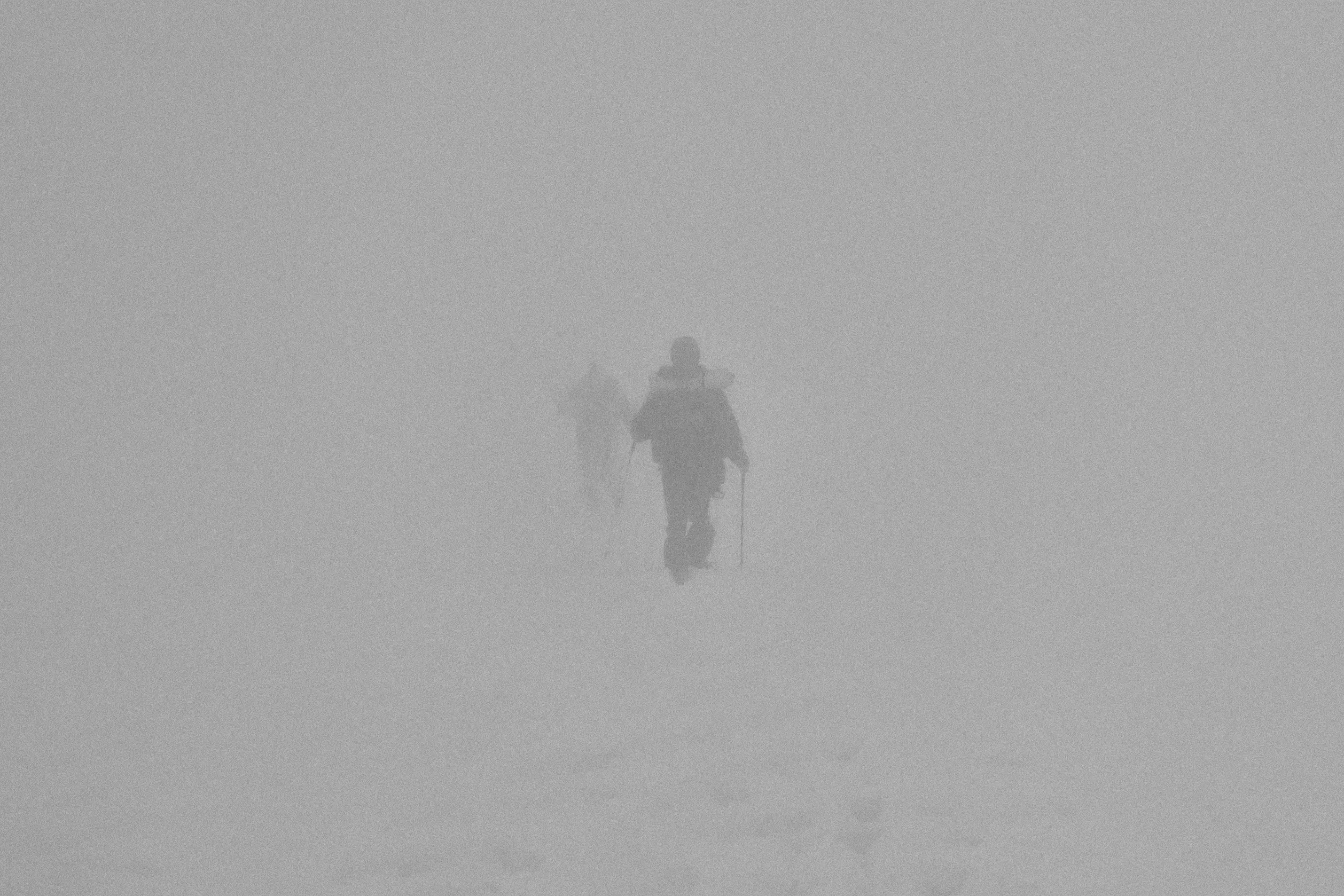 Hegymászók haladnak át egy hómezőn, nagy ködben