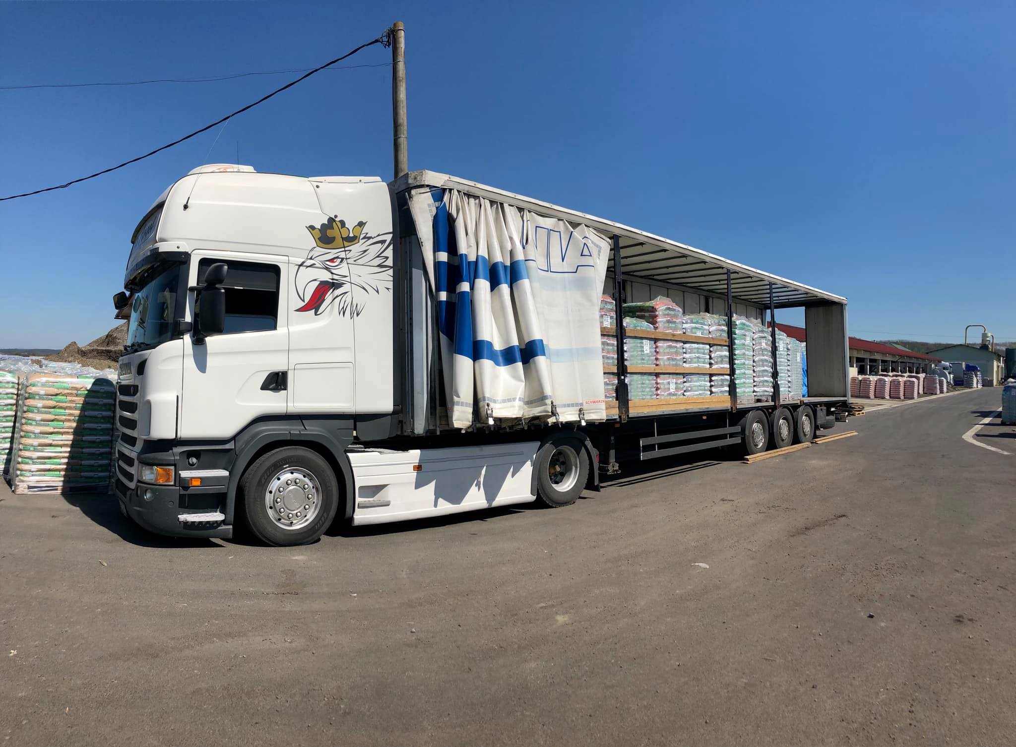 Egy áruszállítási, fuvarozási kamion lerakodás előtt egy úton áll