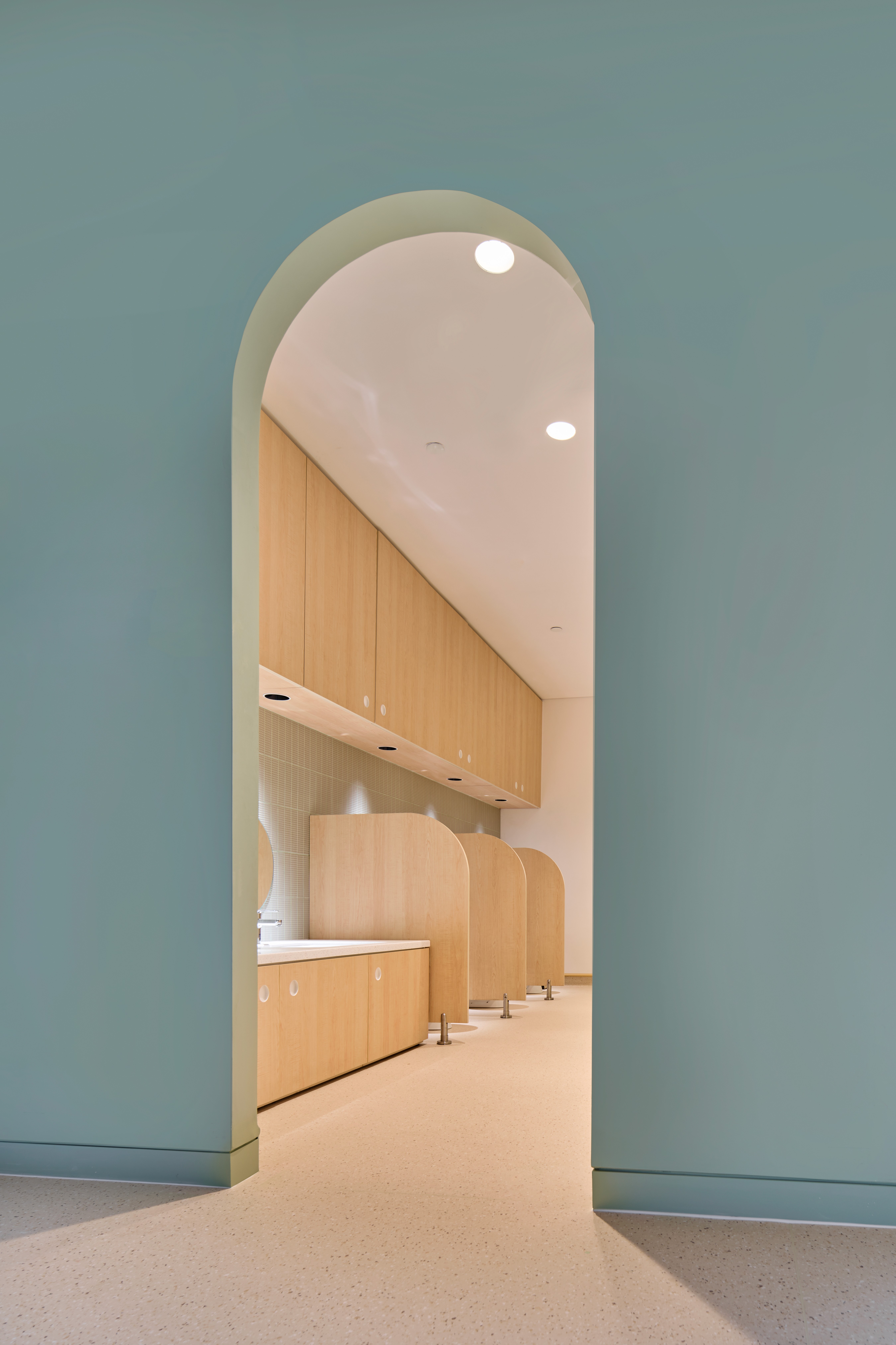 A minimalist archway characterized by clean lines leading into a bathroom with warm wooden wall panels.
