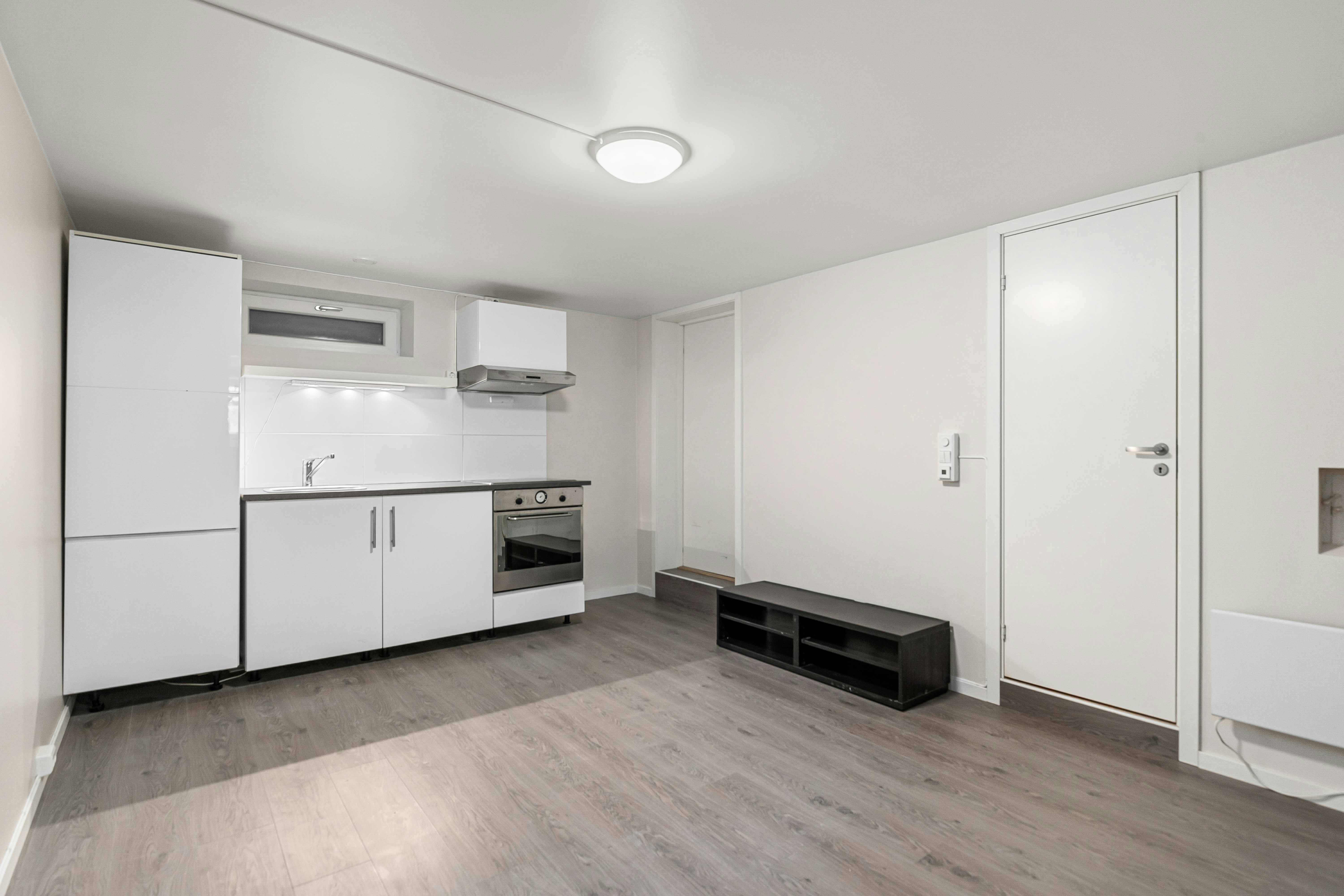 An empty room with white cupboards and white appliances