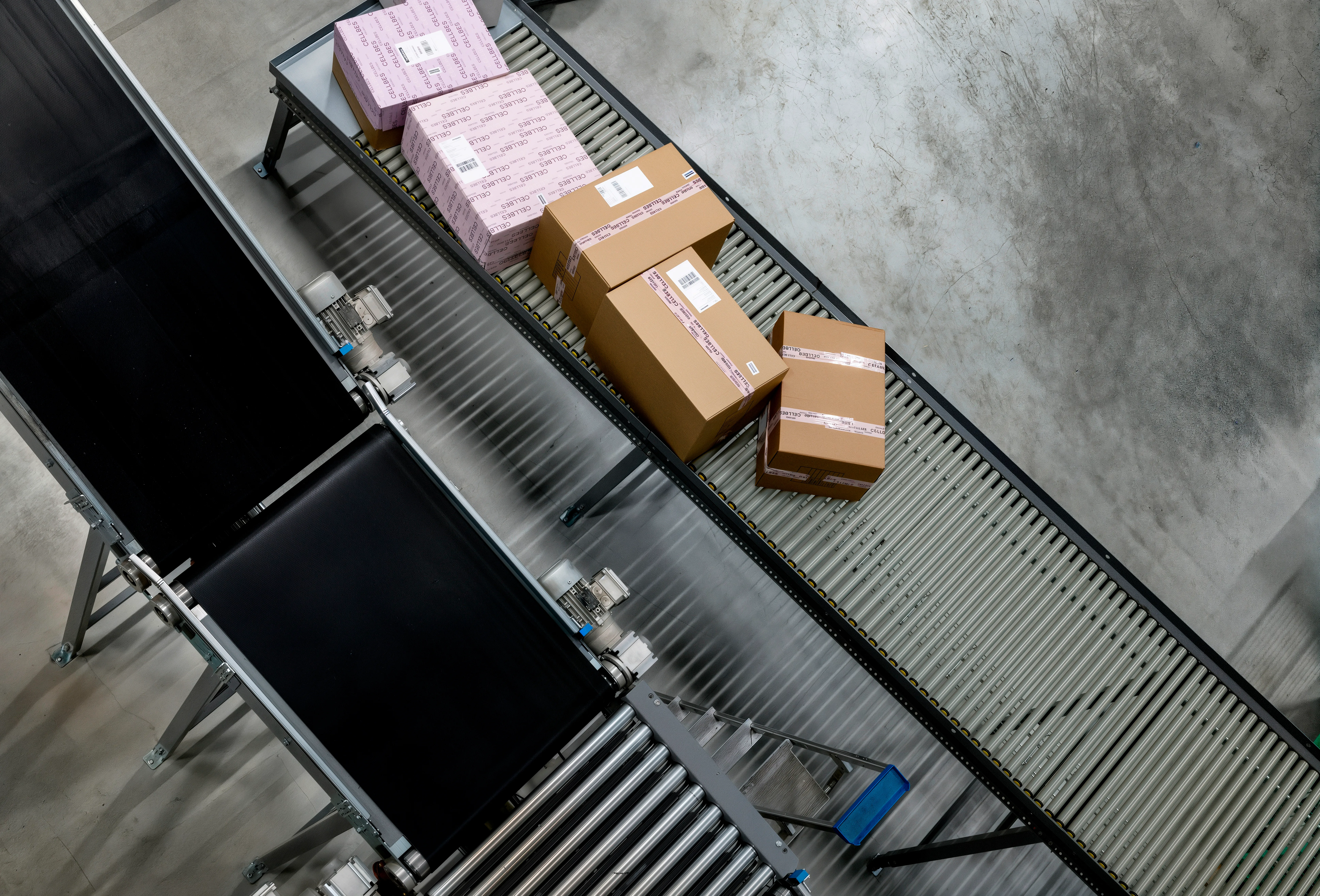 Paket på transportband sorteras i lager. Flera kartonger med fraktetiketter redo för leverans.