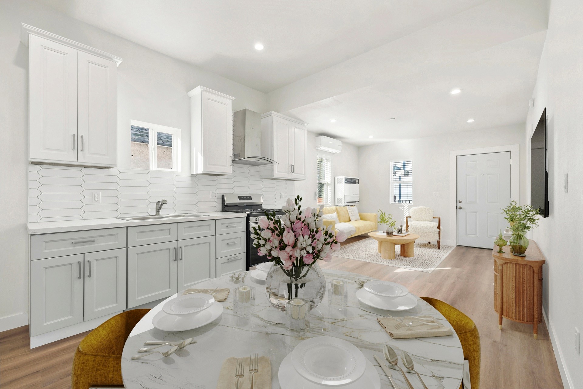 Bright open living room with modern kitchen, white cabinetry, and wide plank floors at 1038 E 53rd
