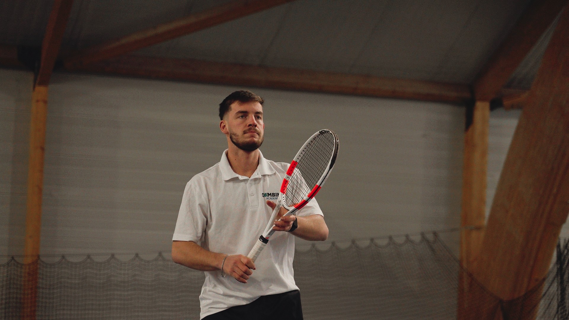 Aurélien Arlot concentré, tenant sa raquette lors d’un entraînement de tennis en intérieur.