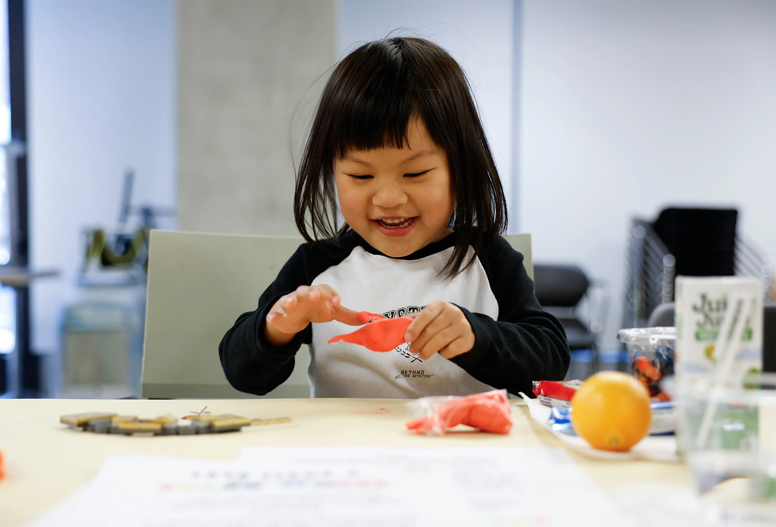 Child happily playing with orange playdough.