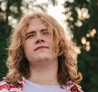 a man with long hair wearing a red and white sweater