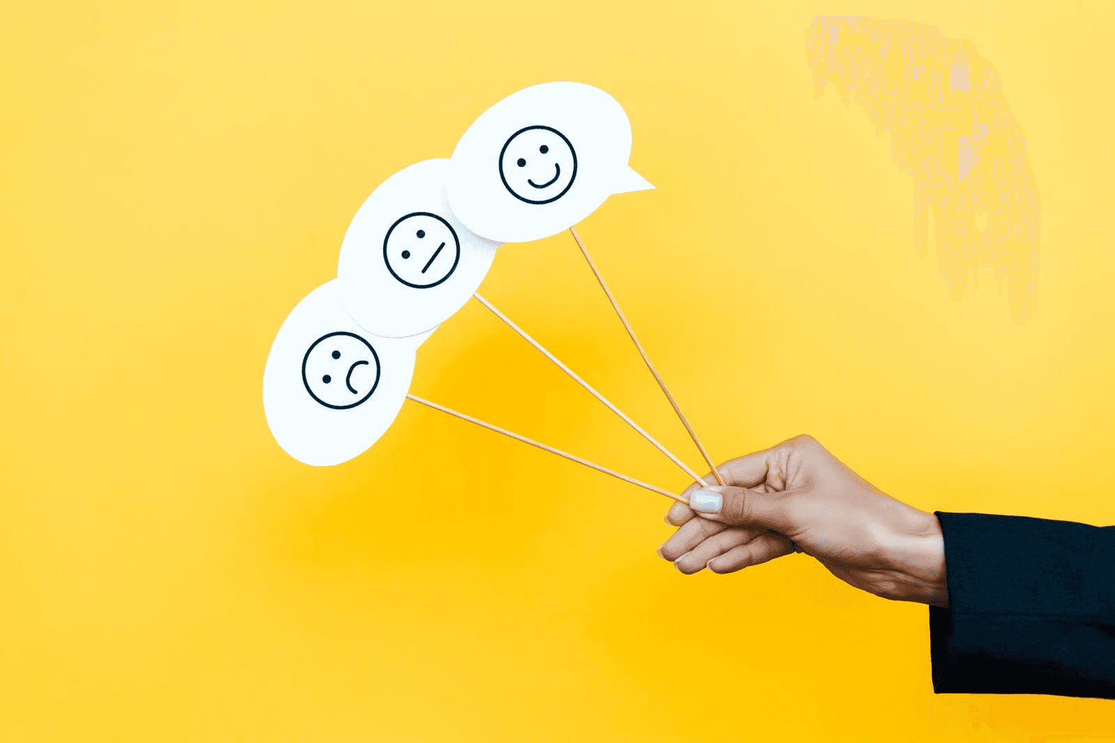 a guy holding feedback emojis in hand in yellow background.