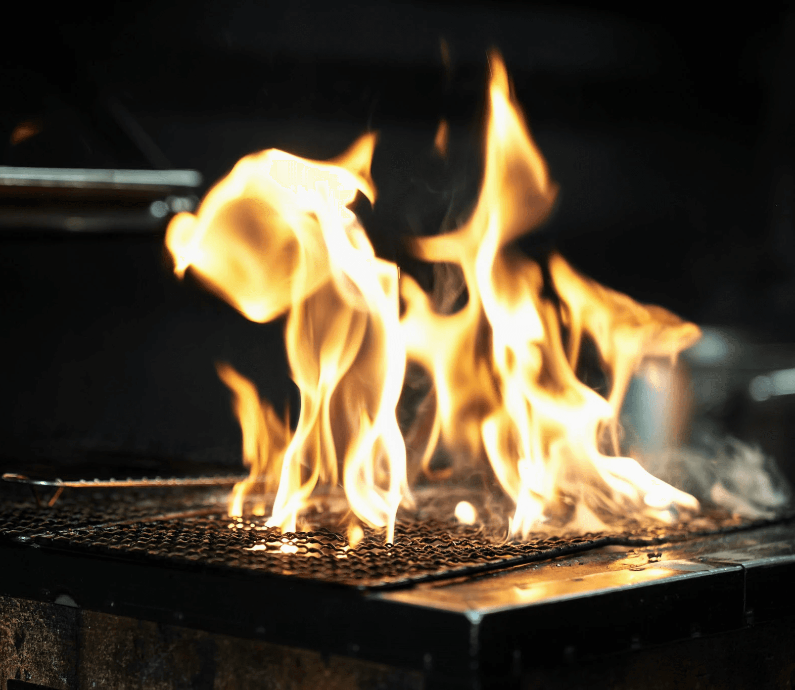 Flammes vives sur le grill de braise du restaurant LAVA, cuisine au feu dans le Quartier Latin Paris 5e