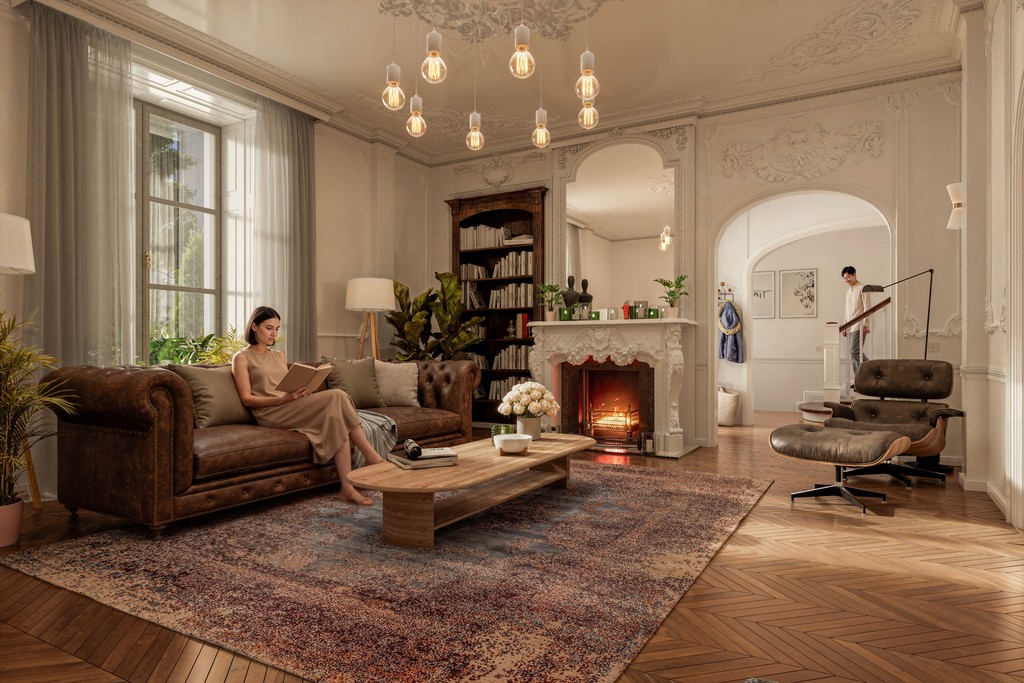 Luxury Parisian-style living room interior design featuring ornate plaster crown mouldings, tufted brown leather Chesterfield sofa, Eames lounge chair, herringbone hardwood flooring, marble fireplace surround, and Edison bulb pendant lighting