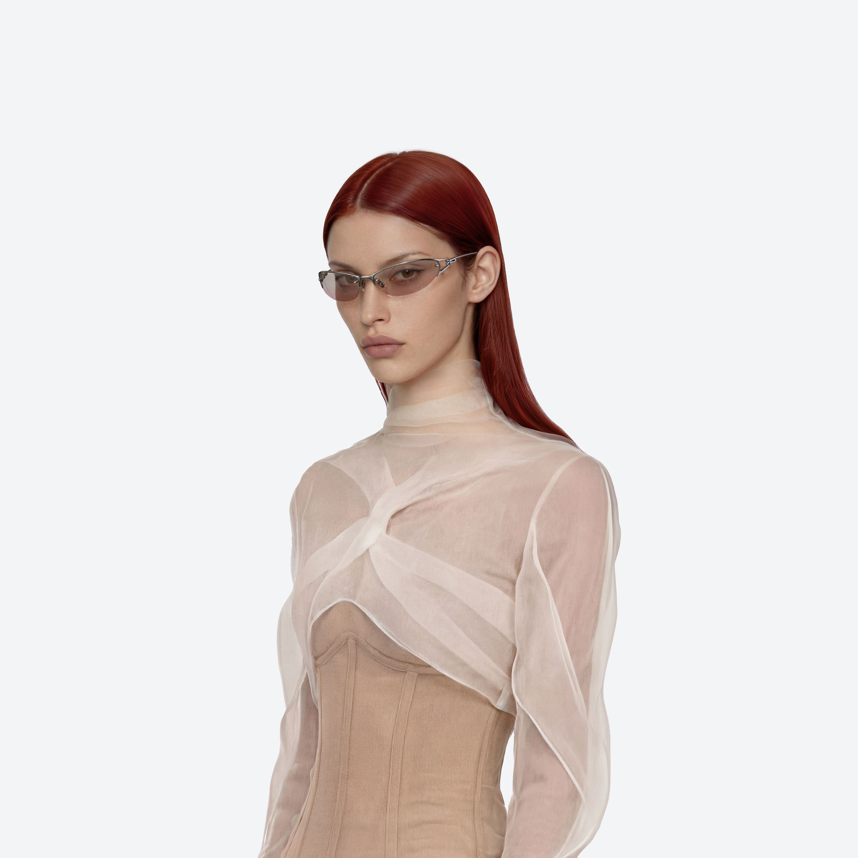 Un mannequin porte les lunettes enveloppantes Pinku 01, monture métal argenté.