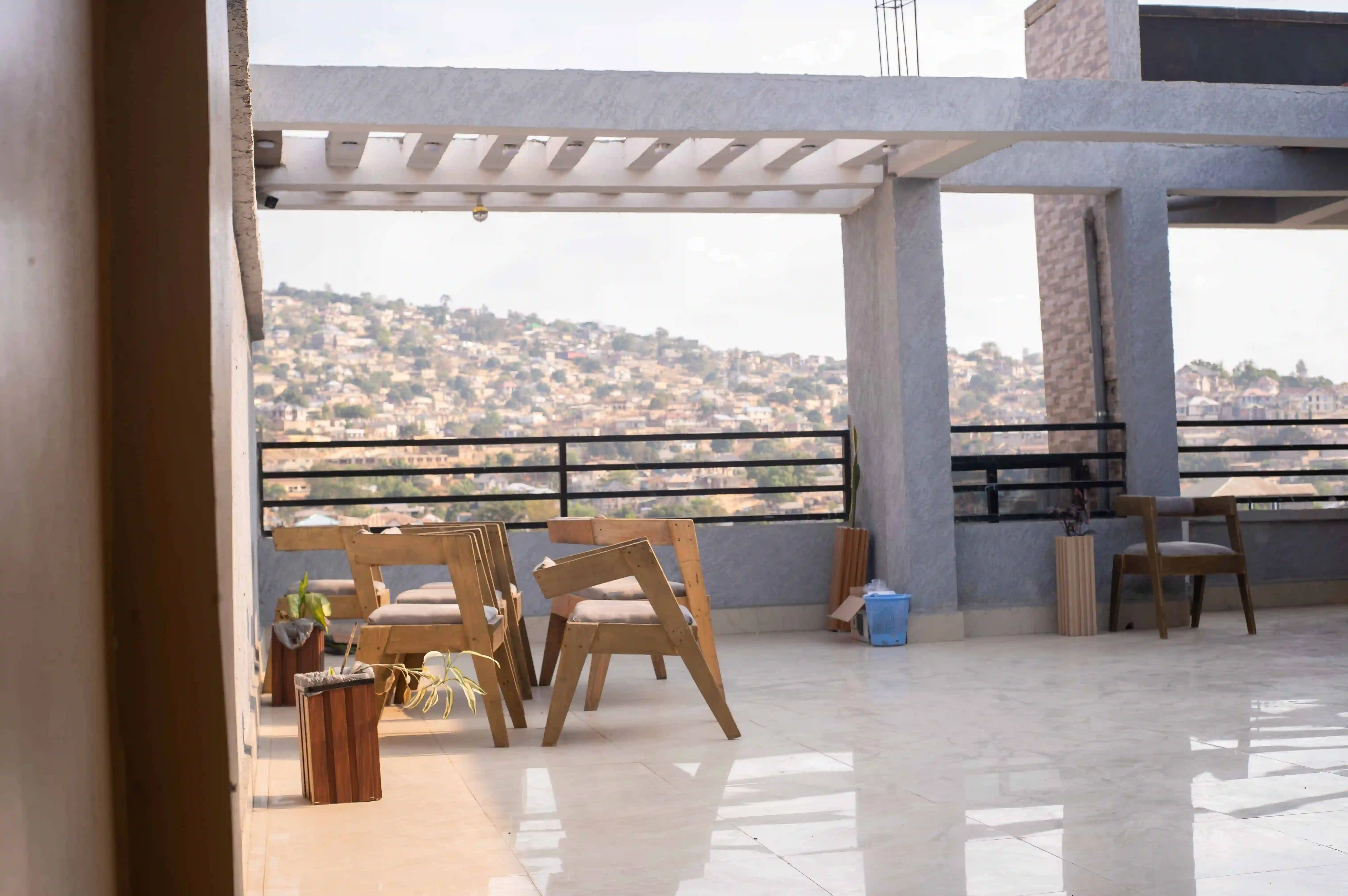 Terrasse couverte avec tables et chaises en bois face aux collines de Matadi.