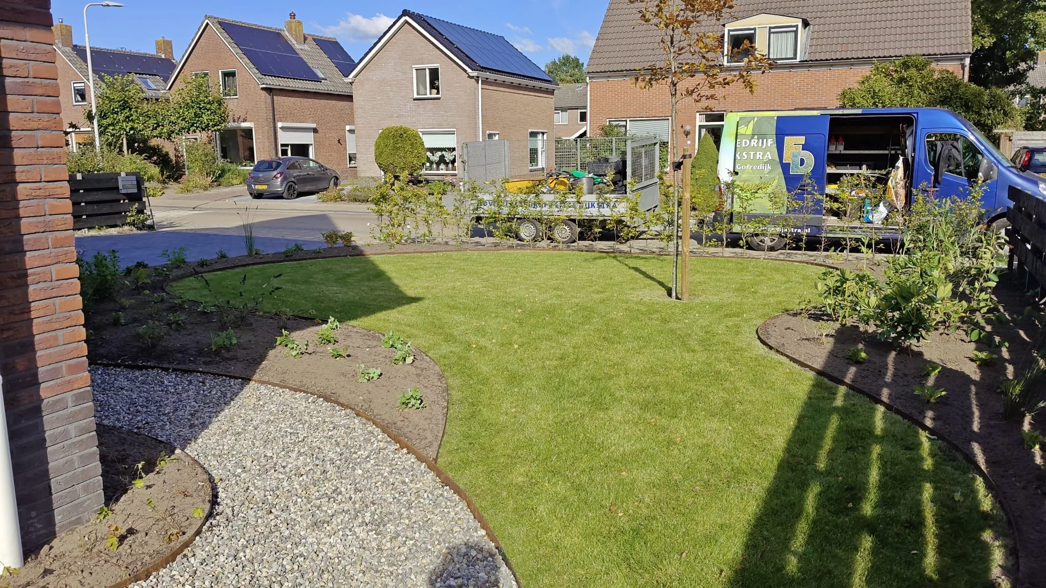 Nieuw aangelegde voortuin met strak gazon, grindpad en jonge beplanting bij vrijstaande nieuwbouwwoning in Lippenhuizen.