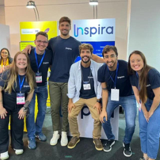 Integrantes do time da Inspira diante do primeiro estande da empresa na Fenalaw, com o letreiro da Inspira ao fundo