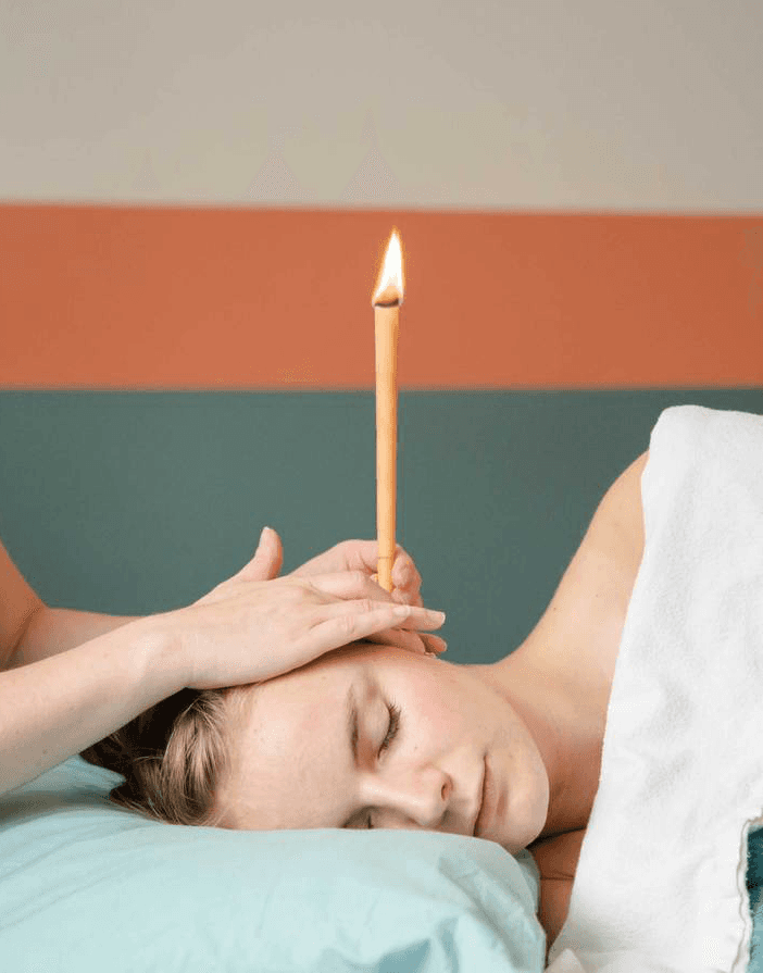 A circle of people sitting cross-legged, meditating with hands in a prayer position. Soft, warm lighting.