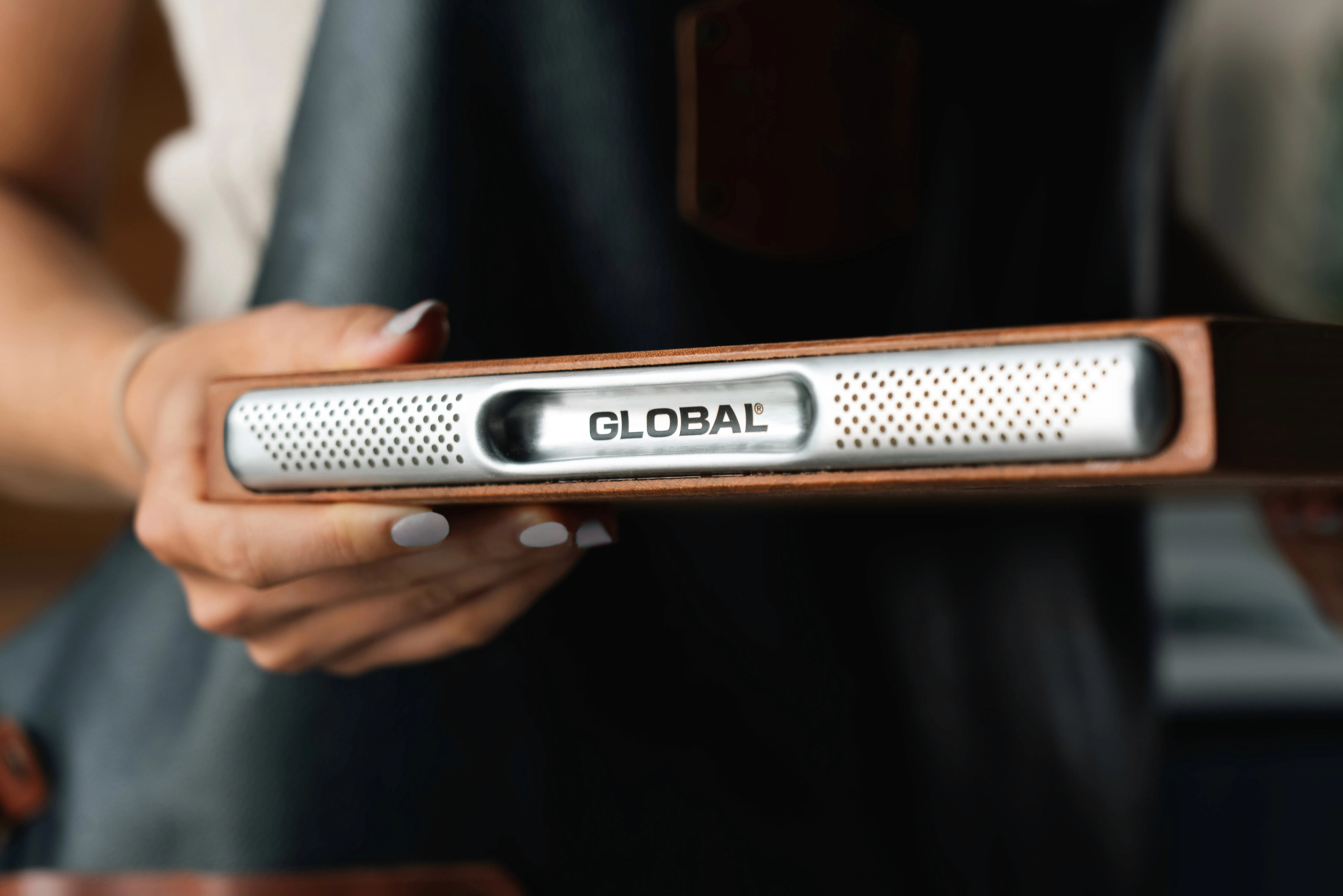 Close-up of GLOBAL cherry wood chopping board handle showing stainless steel detail and wood finish