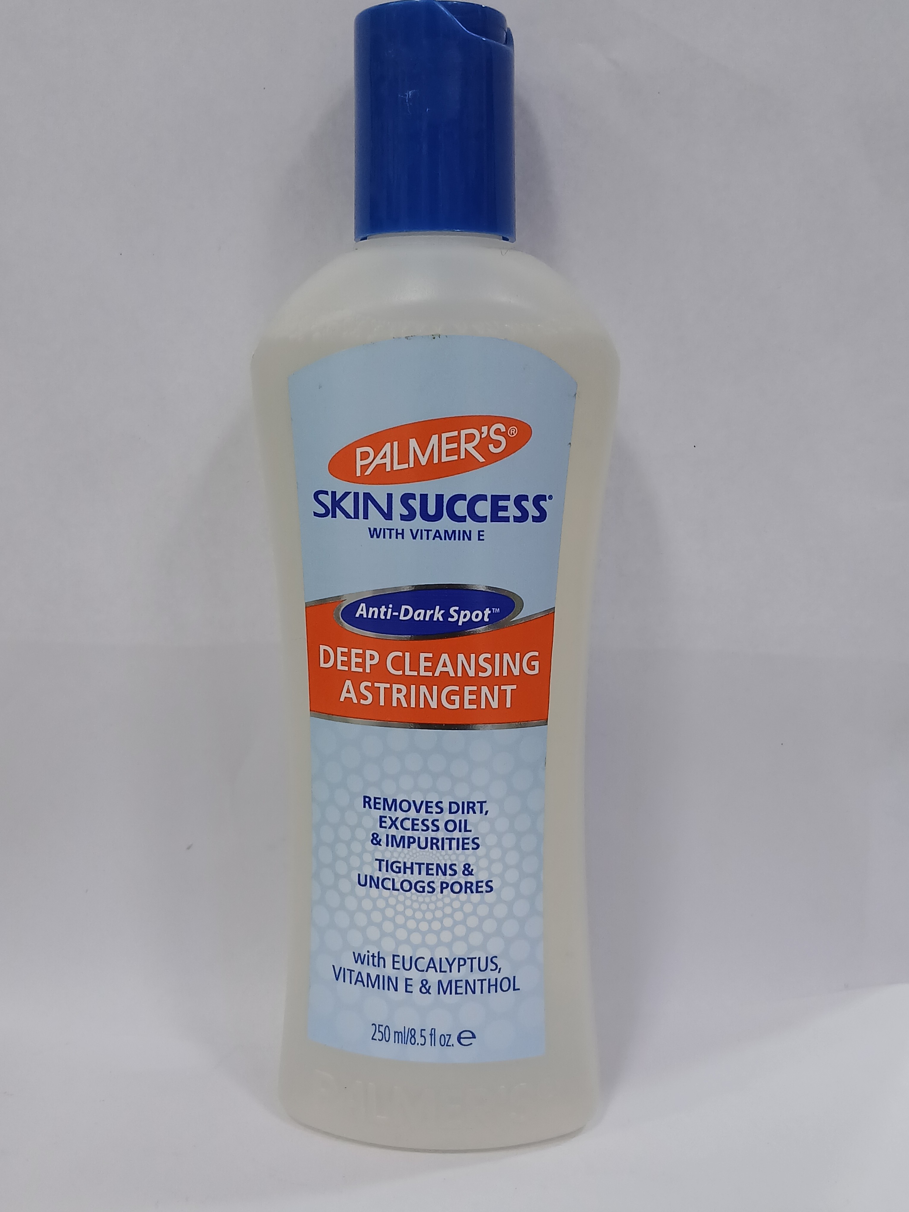 A white pump bottle with a blue cap and orange label featuring text stands against a plain background.