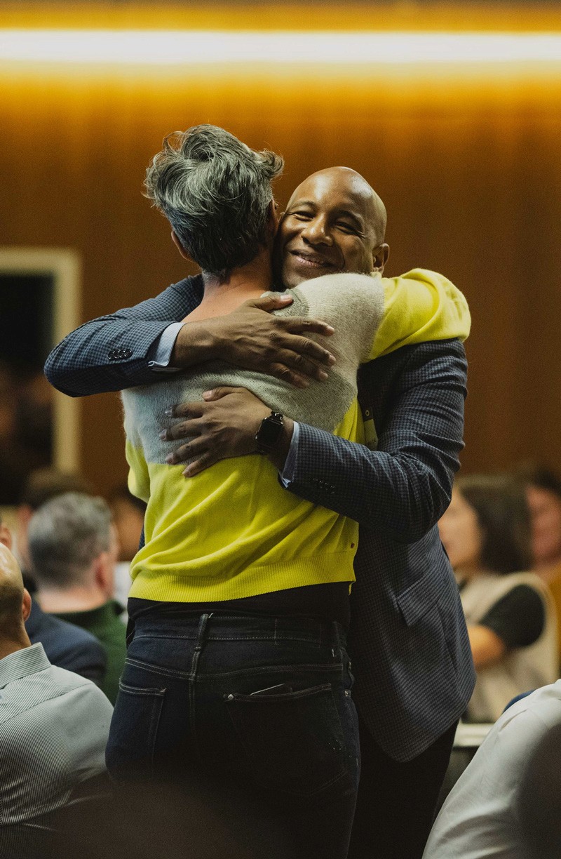 A silhouette of a person wearing sunglasses, with tousled hair, against a teal background.