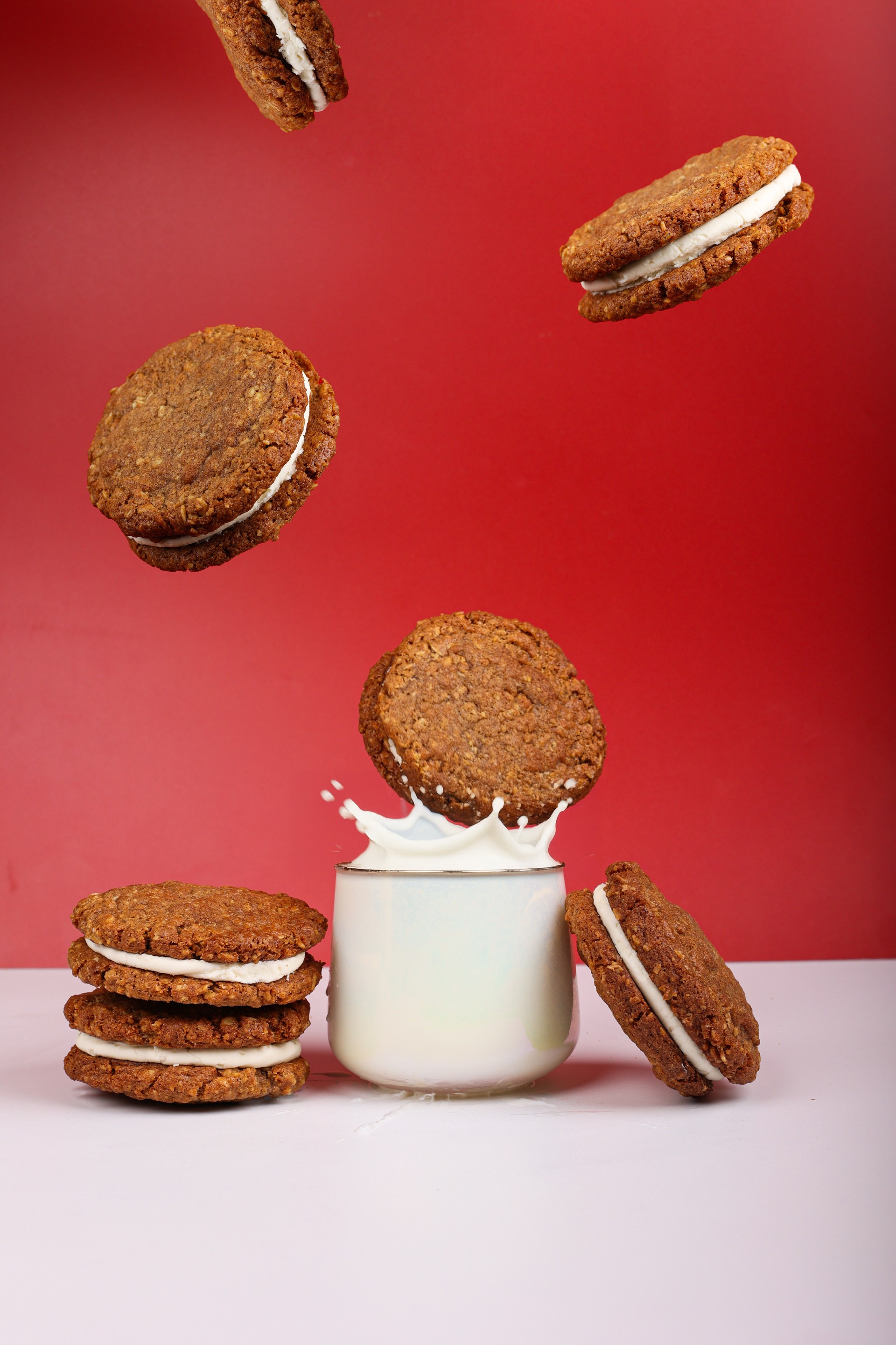 Multiple cookies falling into a big glass of milk