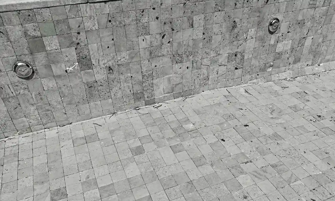 Detalle técnico del interior de una pileta de hormigón vacía, mostrando la prolija colocación de las baldosas de Piedra Bali y los retornos de agua.