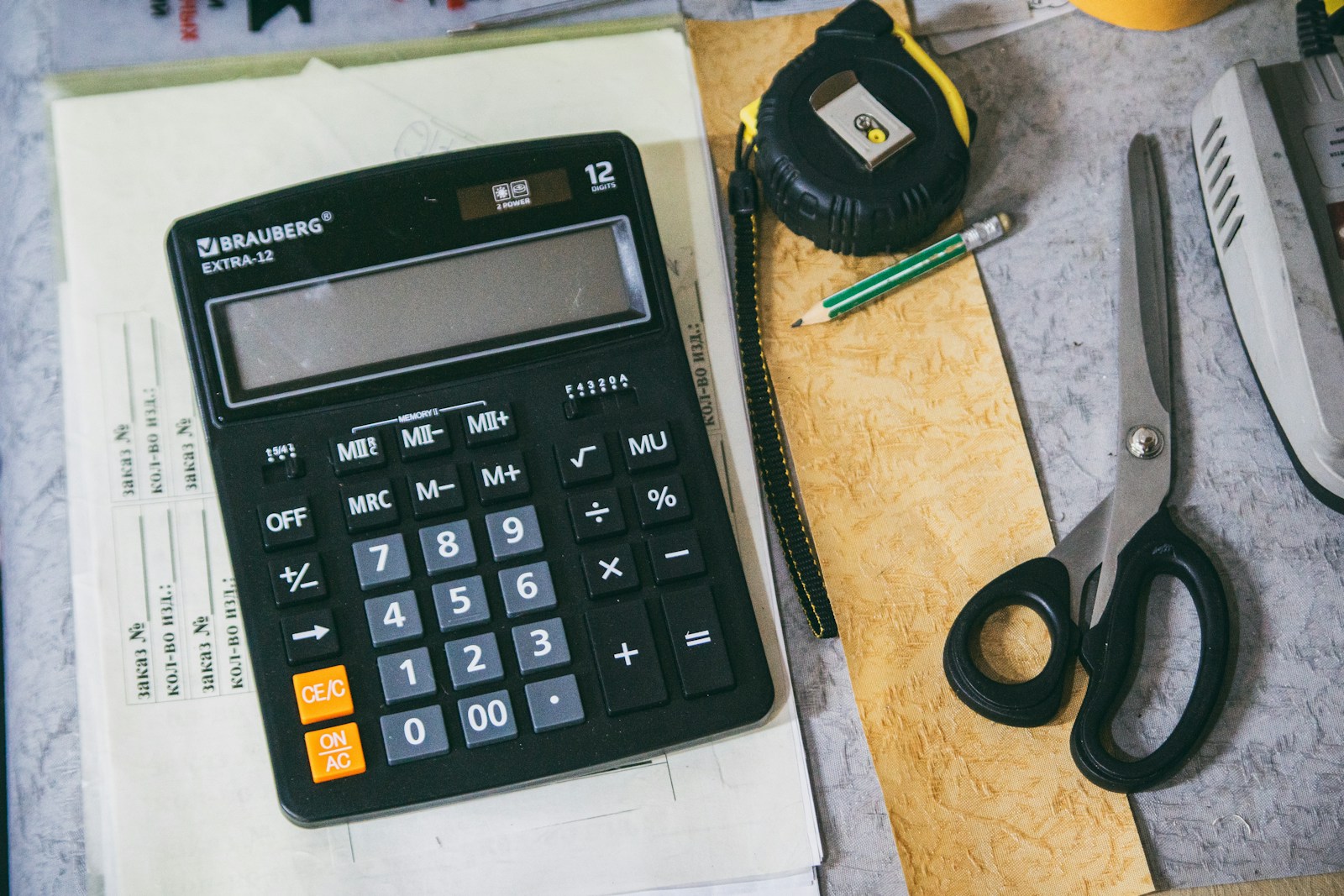 Warm office desk with calculator, paperwork, notebook, and accounting supplies