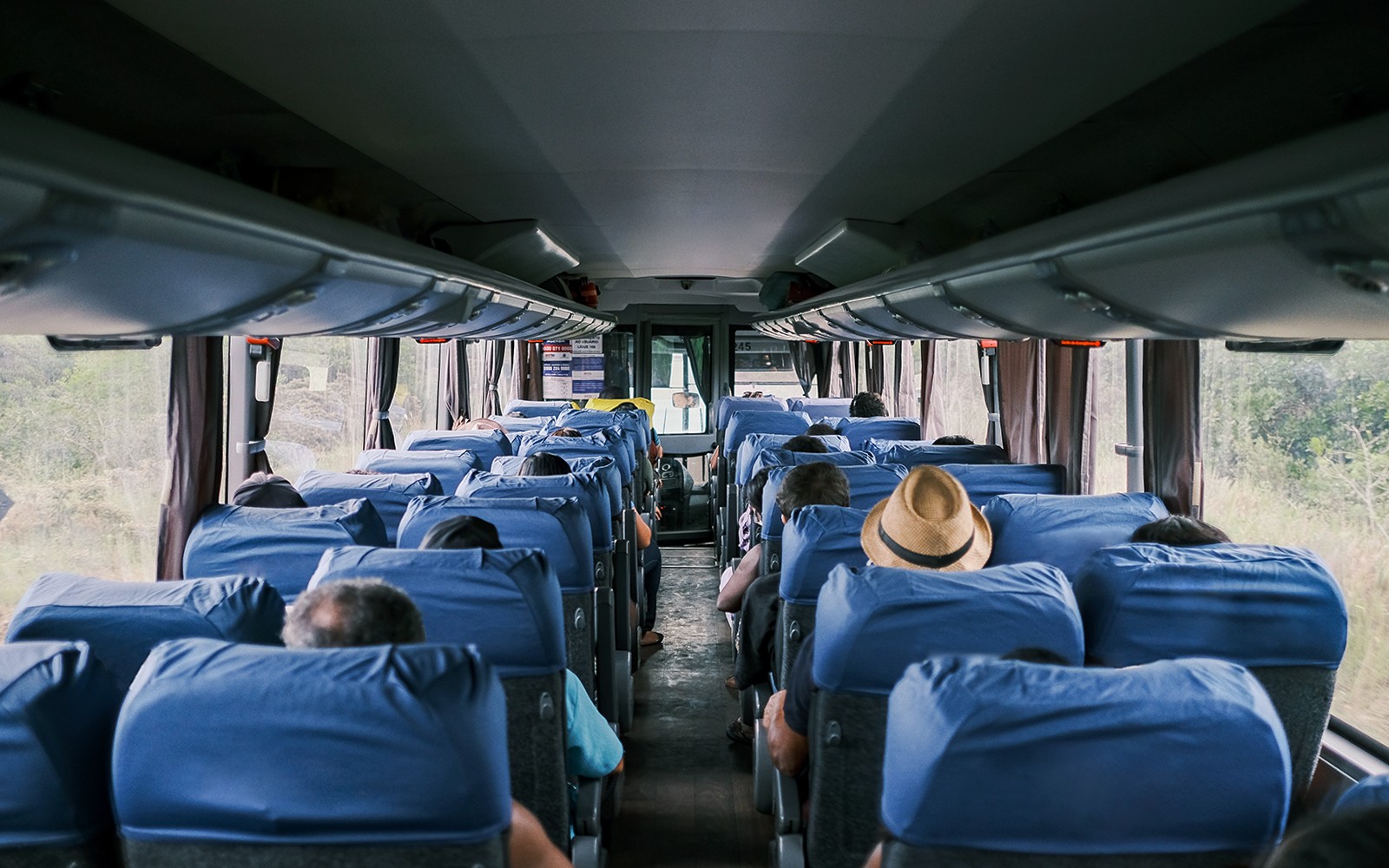 Passengers seated inside a tour bus traveling from Paris to Mont St. Michel's Abbey.