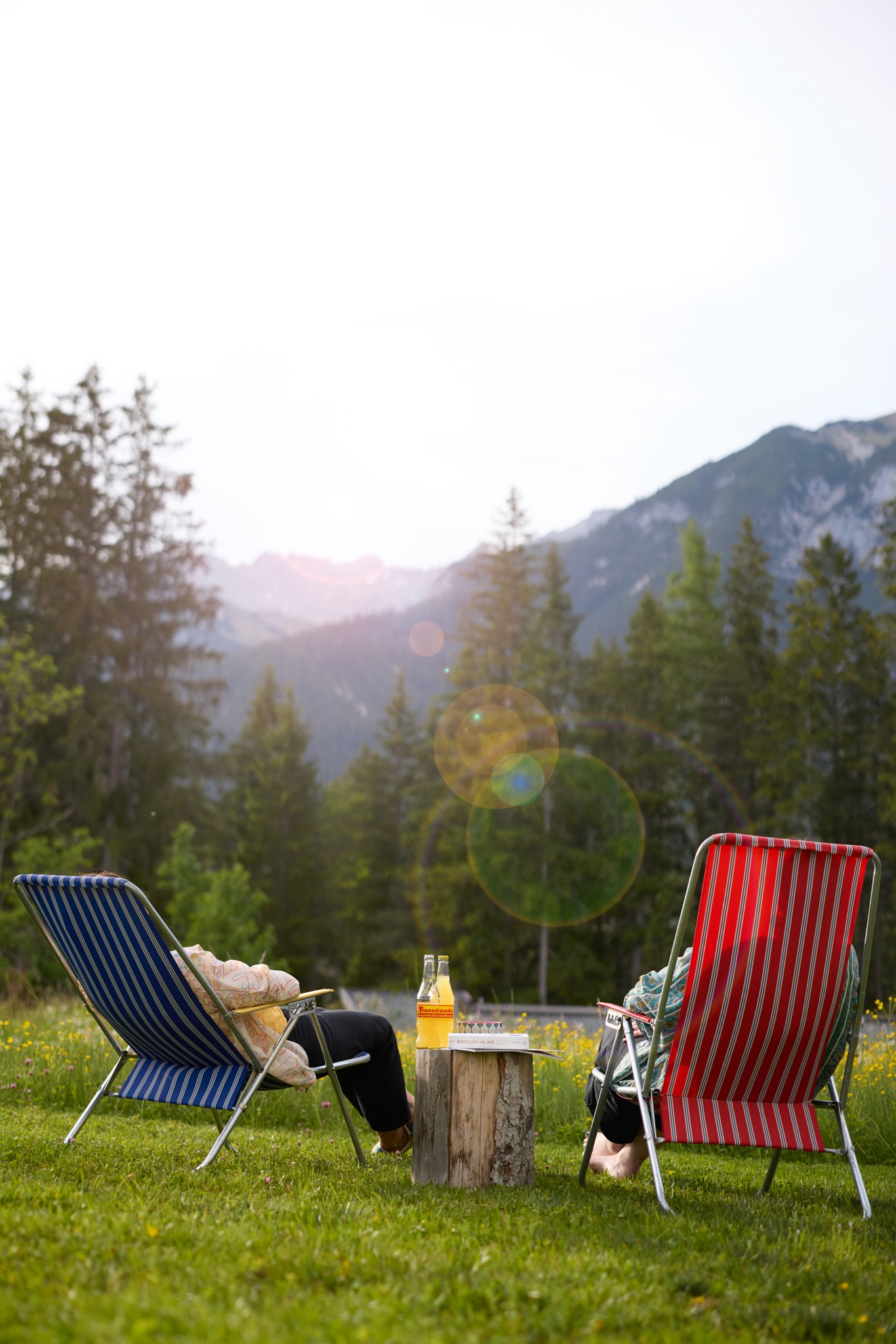 garten mit liegestühlen auf denen menschen liegen getränke 