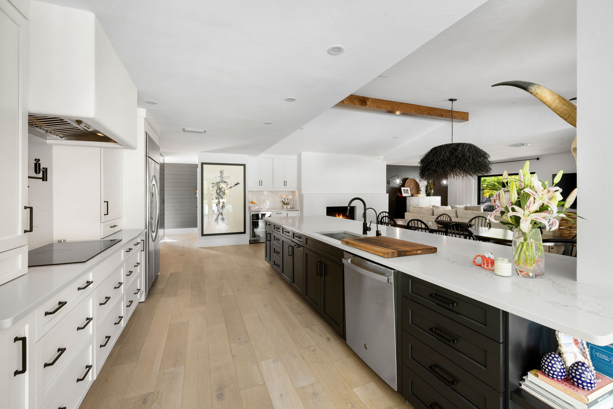 a long kitchen island with a blend of black and white cabinets and light wooden floors