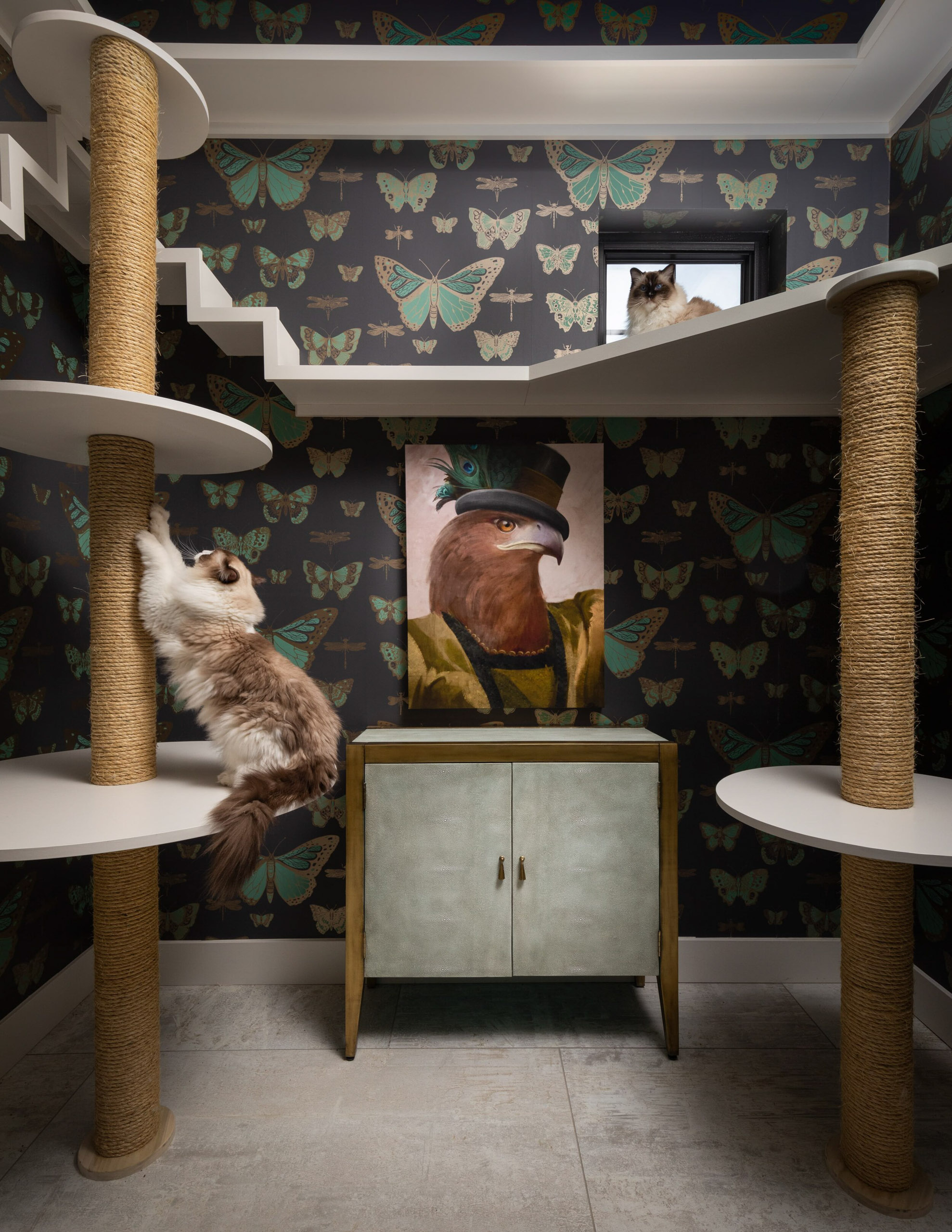 Cat tree with two cats and eagle portrait artwork.