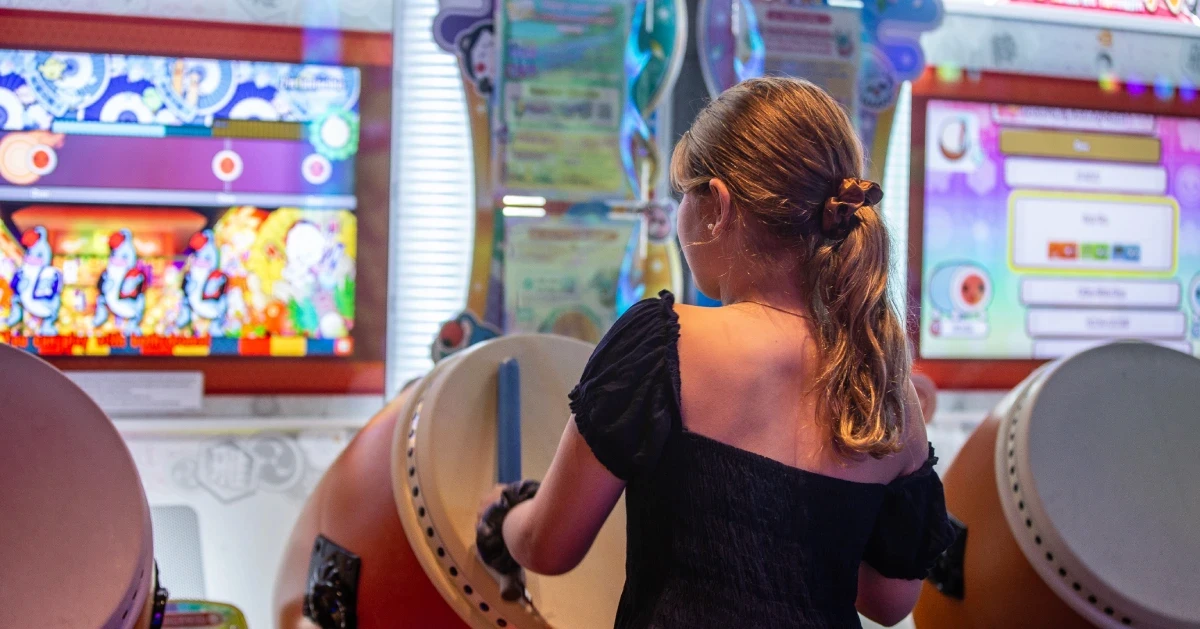 A woman playing Taiko no Tatsujin on the arcade drums