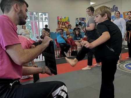 Instructor holding a board as a student attempts to break it with a kick.