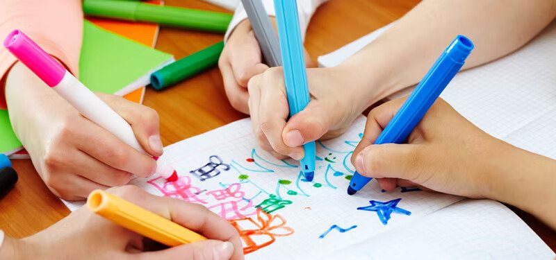 Enfants dessinant au feutre sur du papier