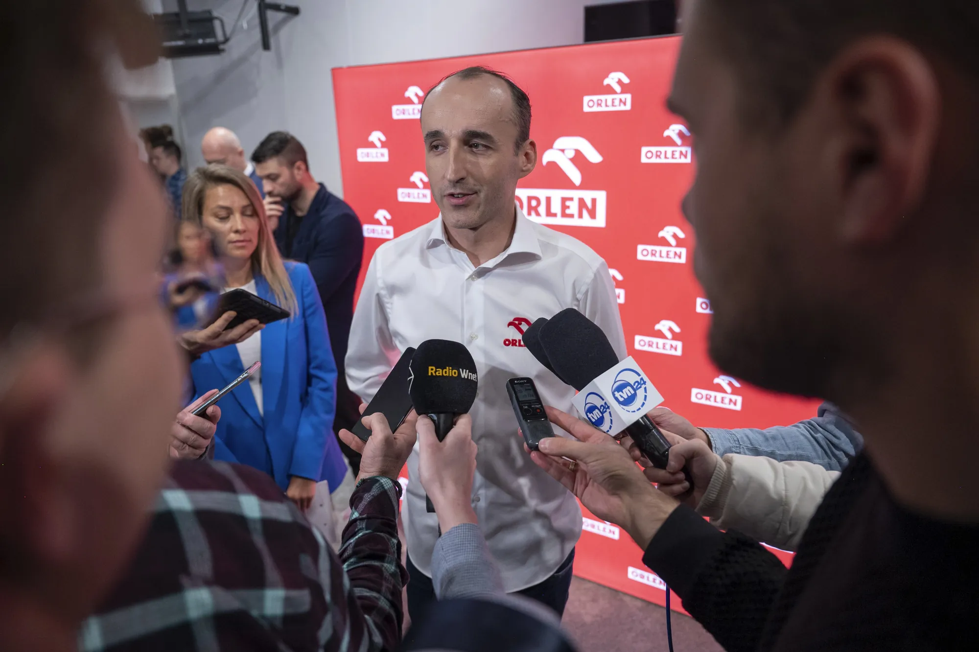 Robert Kubica przed mikrofonami mediów podczas konferencji prasowej ORLEN.