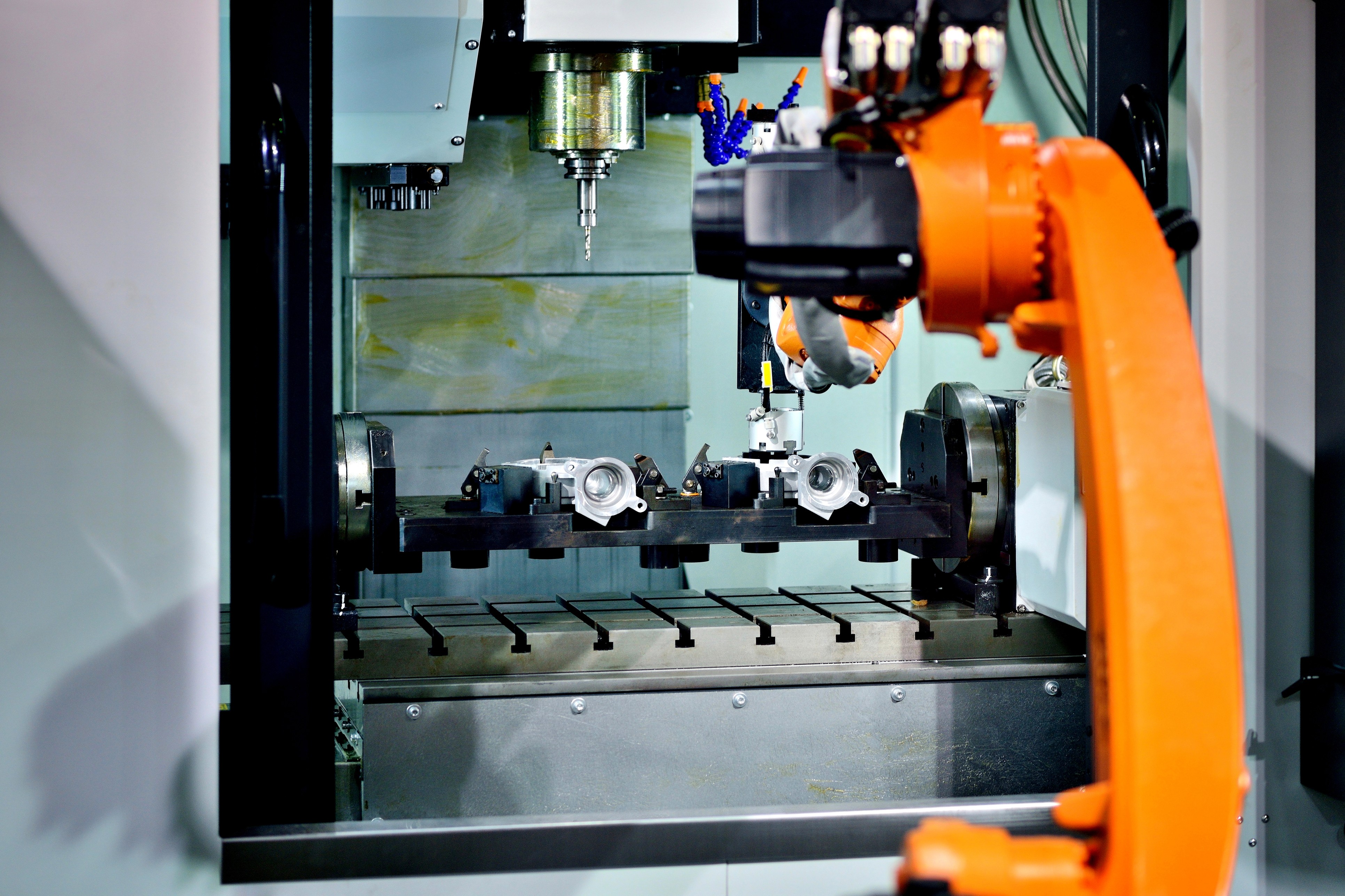 An orange robotic arm is positioned near a control panel with various components and screens.