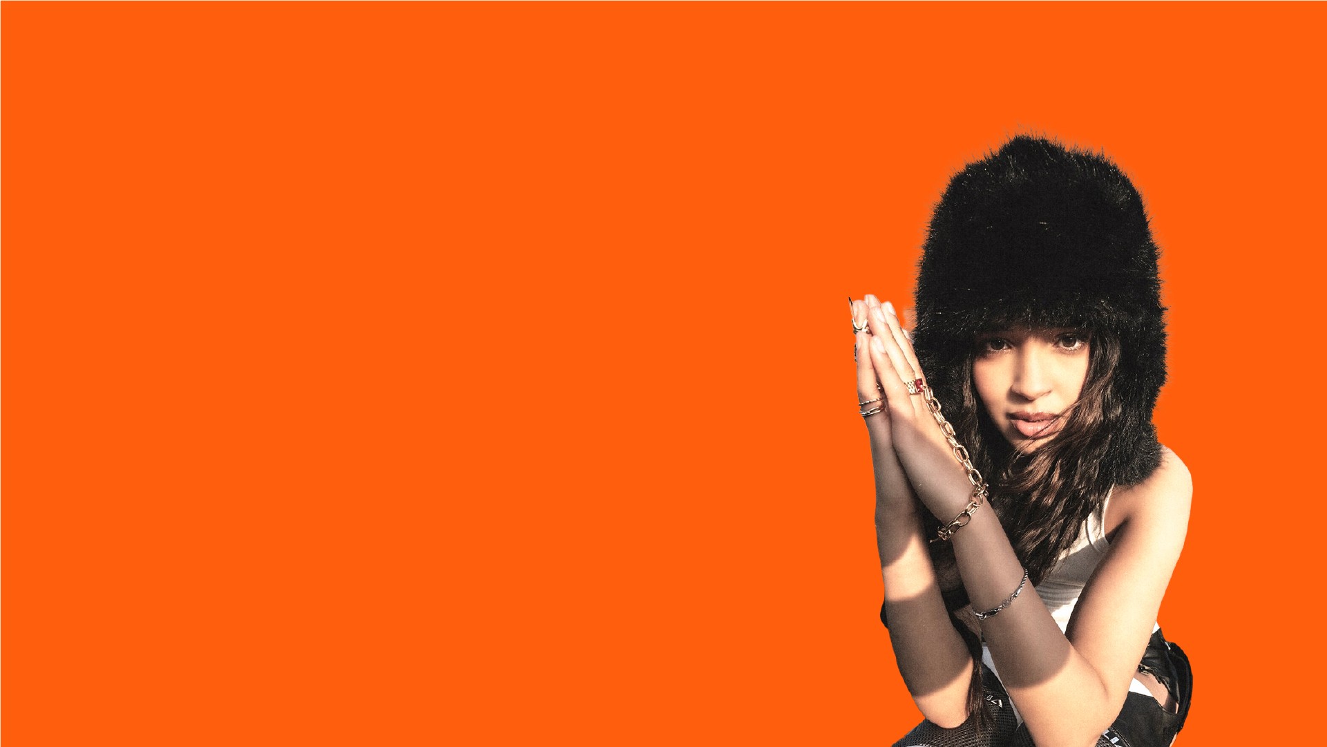 Bannière au format panoramique avec un fond uni orange vif (couleur d'identité de TopLine). À droite, un portrait tronqué et stylisé d'une artiste musicale (rap/pop) ou d'une influenceuse. Elle porte un bonnet en fausse fourrure noire et de multiples bagues et chaînes dorées. Ses mains sont jointes devant son visage, créant une pose accrocheuse. L'espace négatif à gauche est dédié au texte. Ce visuel de direction artistique forte est utilisé pour l'identité visuelle et le branding du média digital musical TopLine, mettant en évidence les services de graphisme et de création de contenu de Nux-Studio.